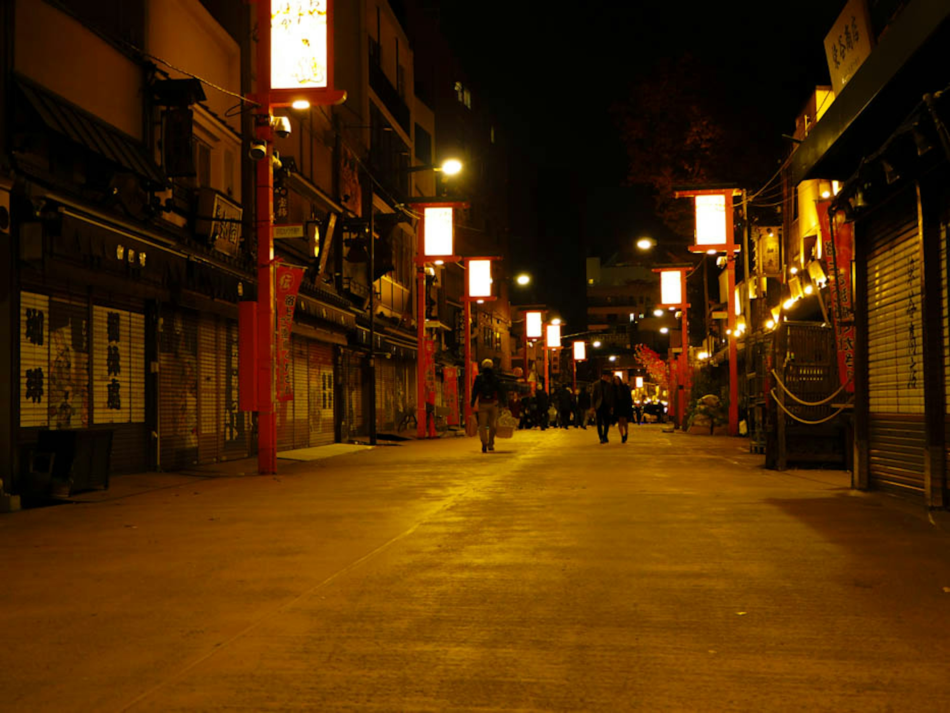 Scène de rue nocturne avec des lanternes rouges et des personnes marchant