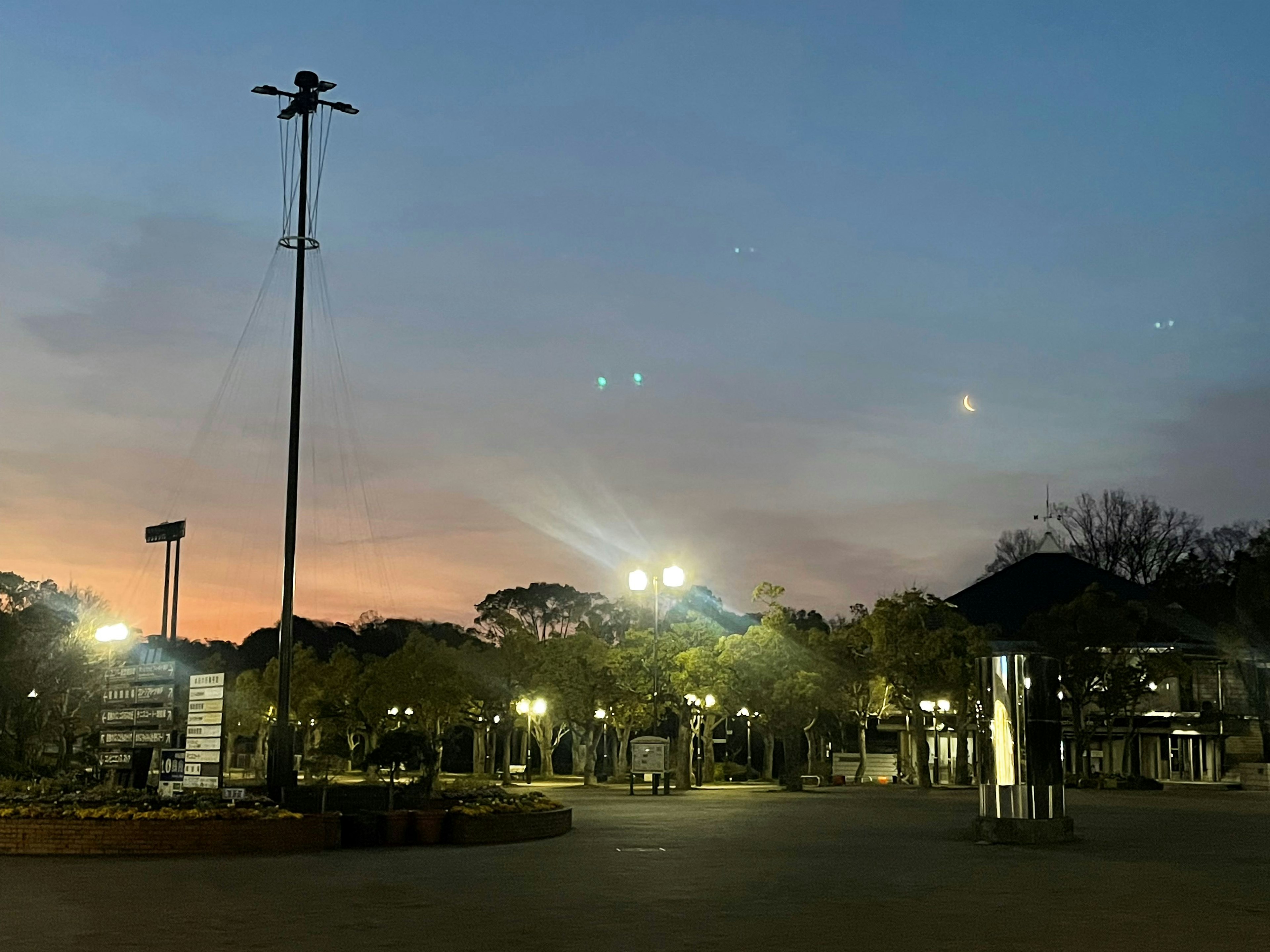 夕焼けの空と街灯が照らす公園の風景