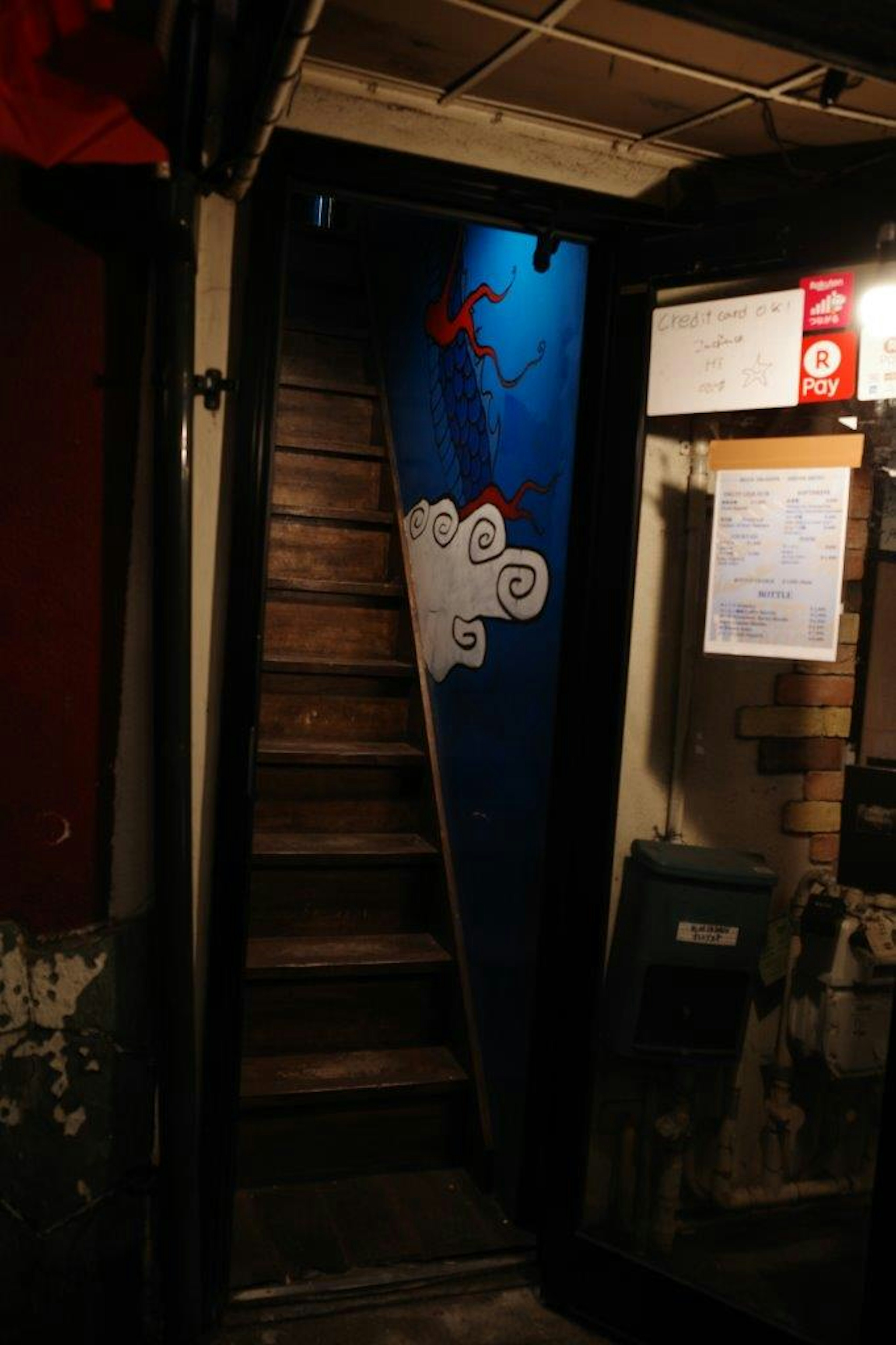 Entrée avec des escaliers en bois menant à un mur bleu avec un motif de nuage blanc