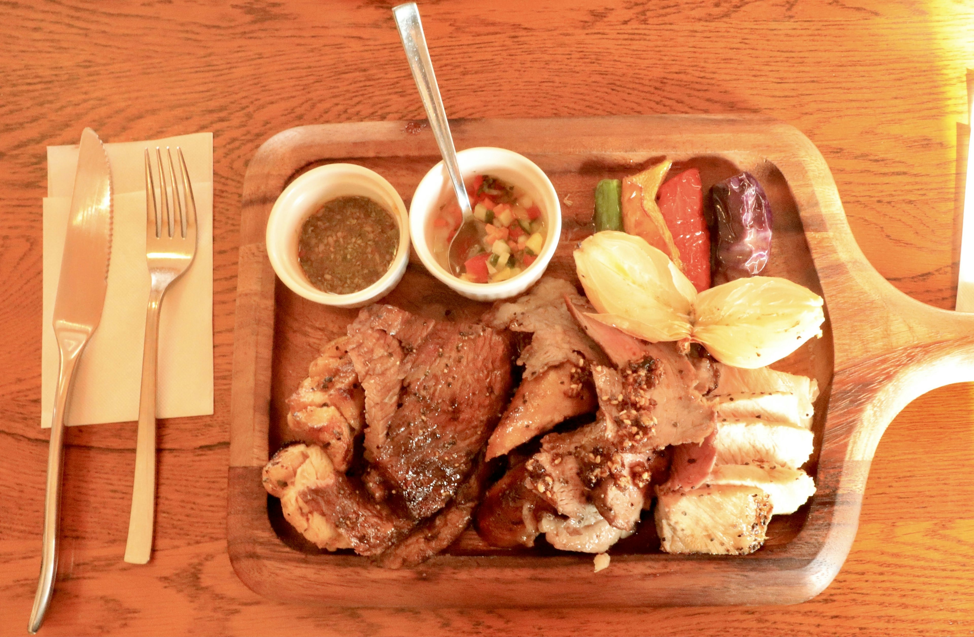 Plato de carne a la parrilla con acompañamientos y salsas