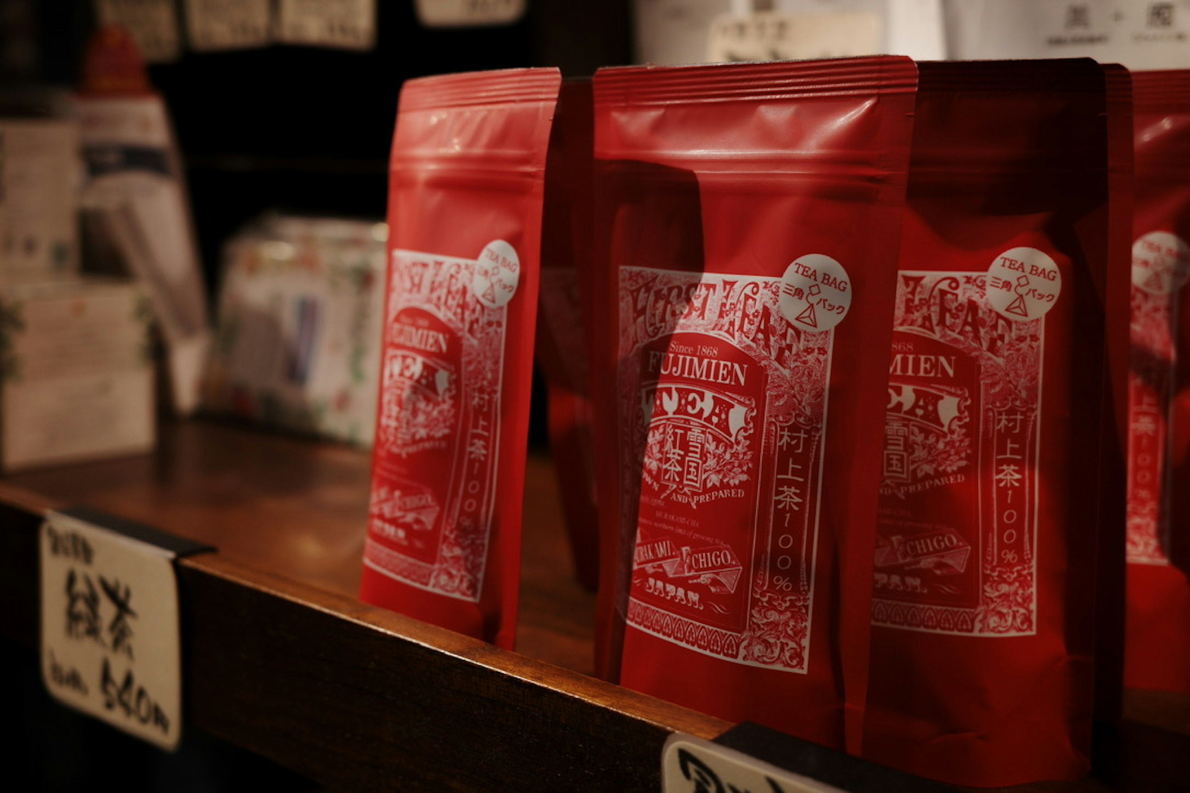 Red coffee bags displayed on a wooden shelf in a shop