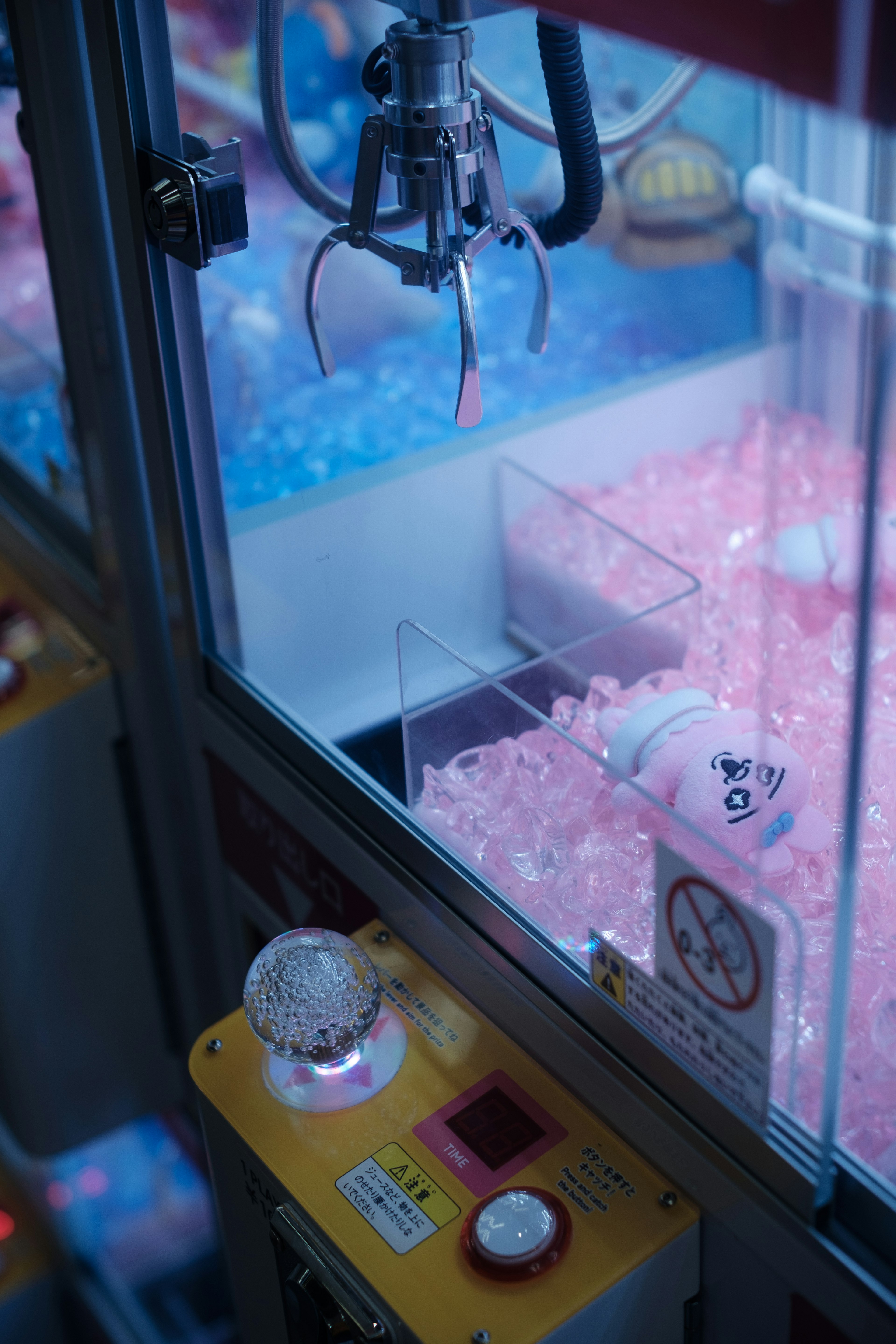 Claw machine with pink beads and a white plush toy visible inside