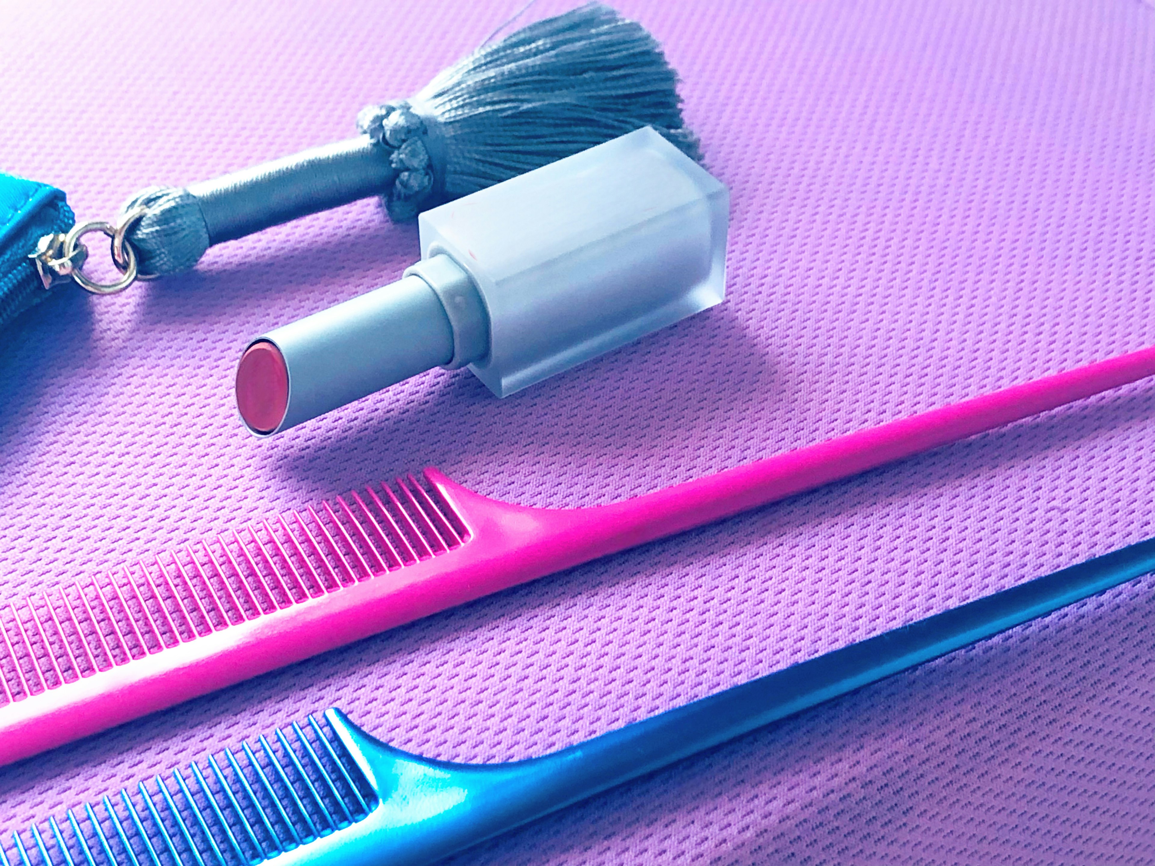 Pink and blue combs and nail polish placed on a purple background