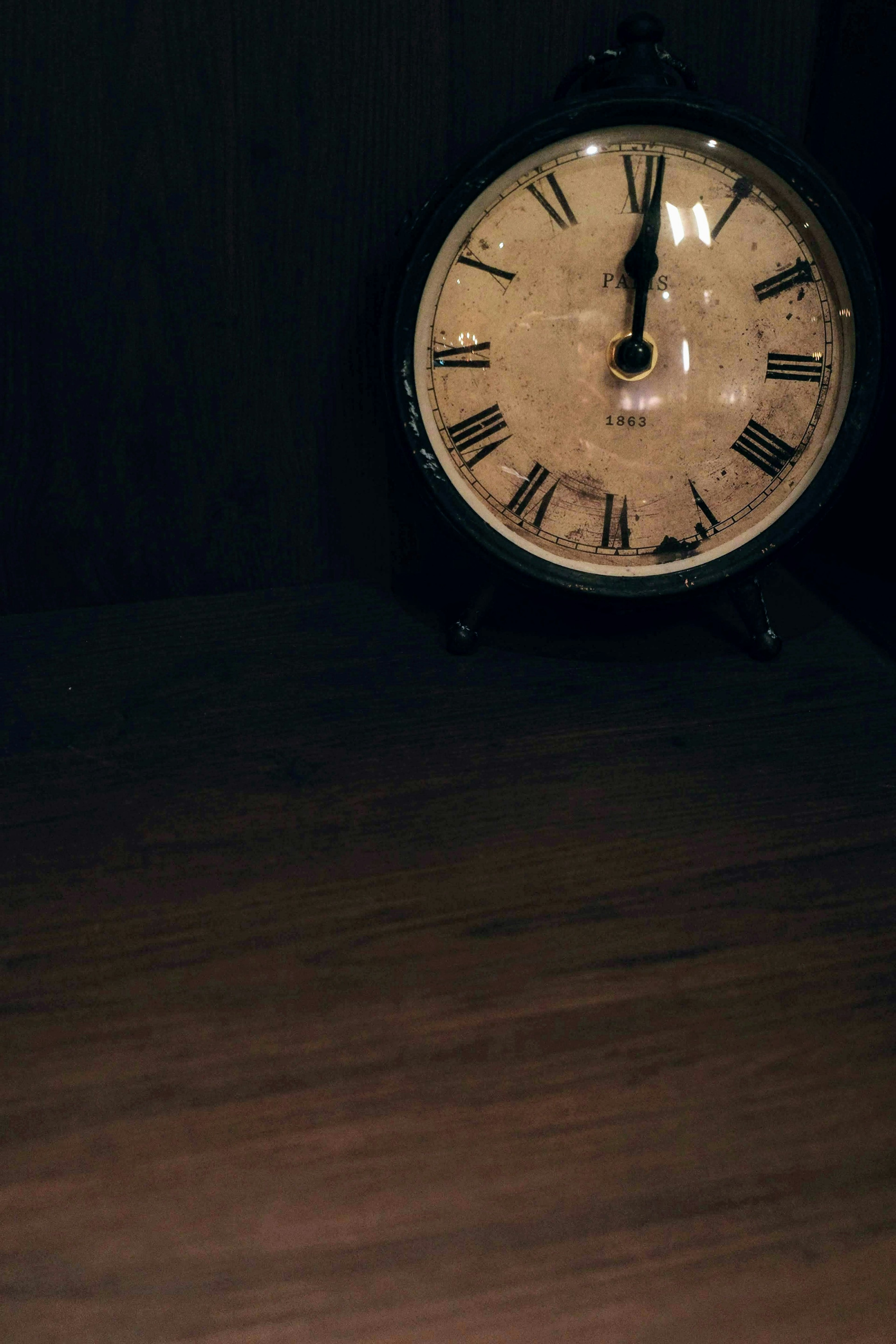 Classic clock on a wooden table featuring Roman numerals and black hands