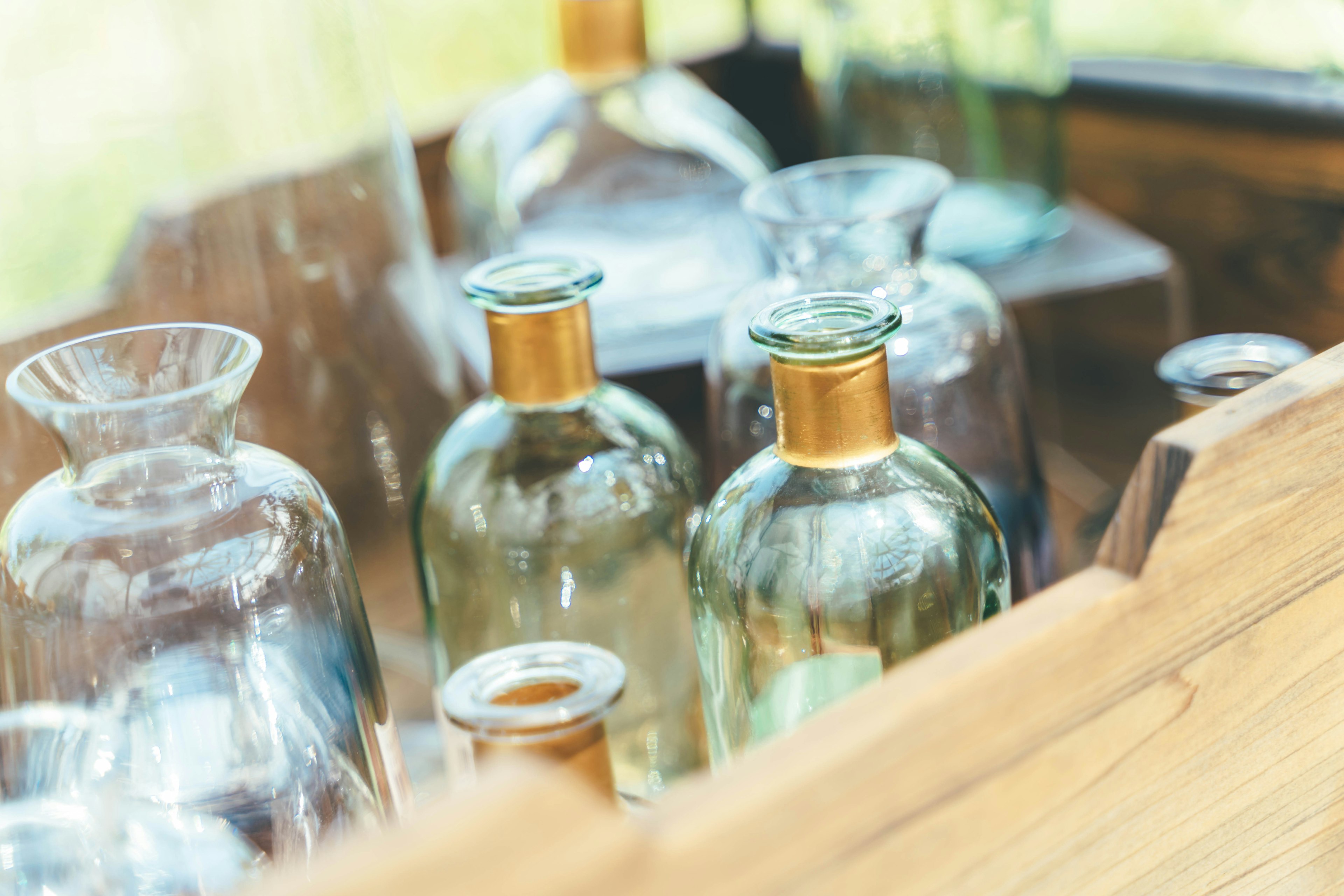 Close-up of glass bottles arranged in a wooden box featuring various shapes and sizes with golden caps