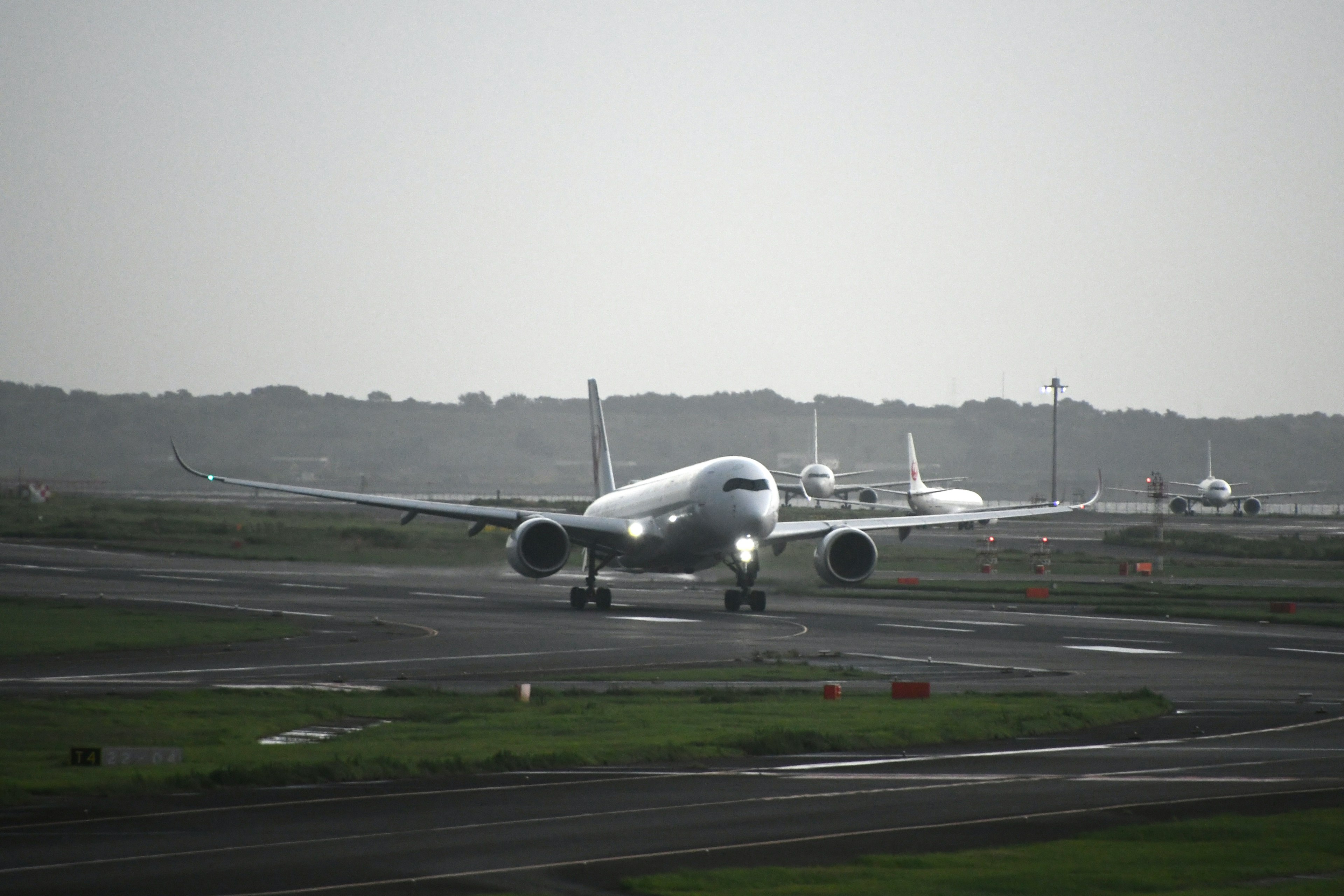 滑走路を走行する航空機と背景に他の航空機を示す風景