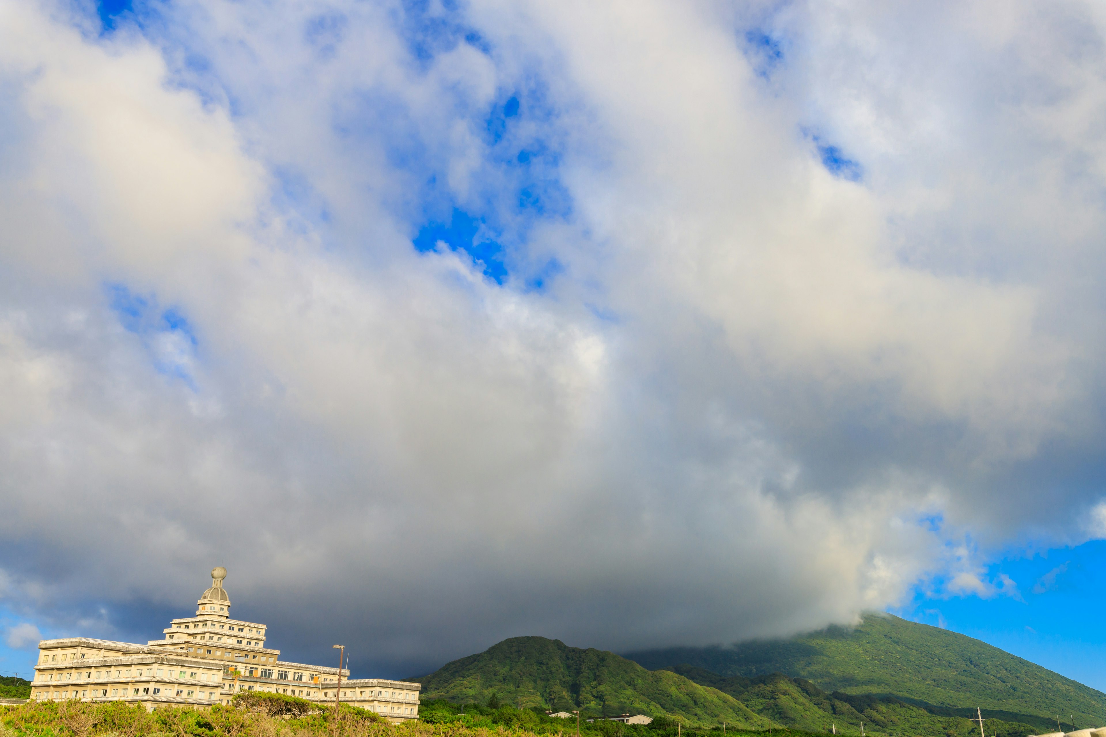 美しい雲と青空の下にある大きな建物と山の風景