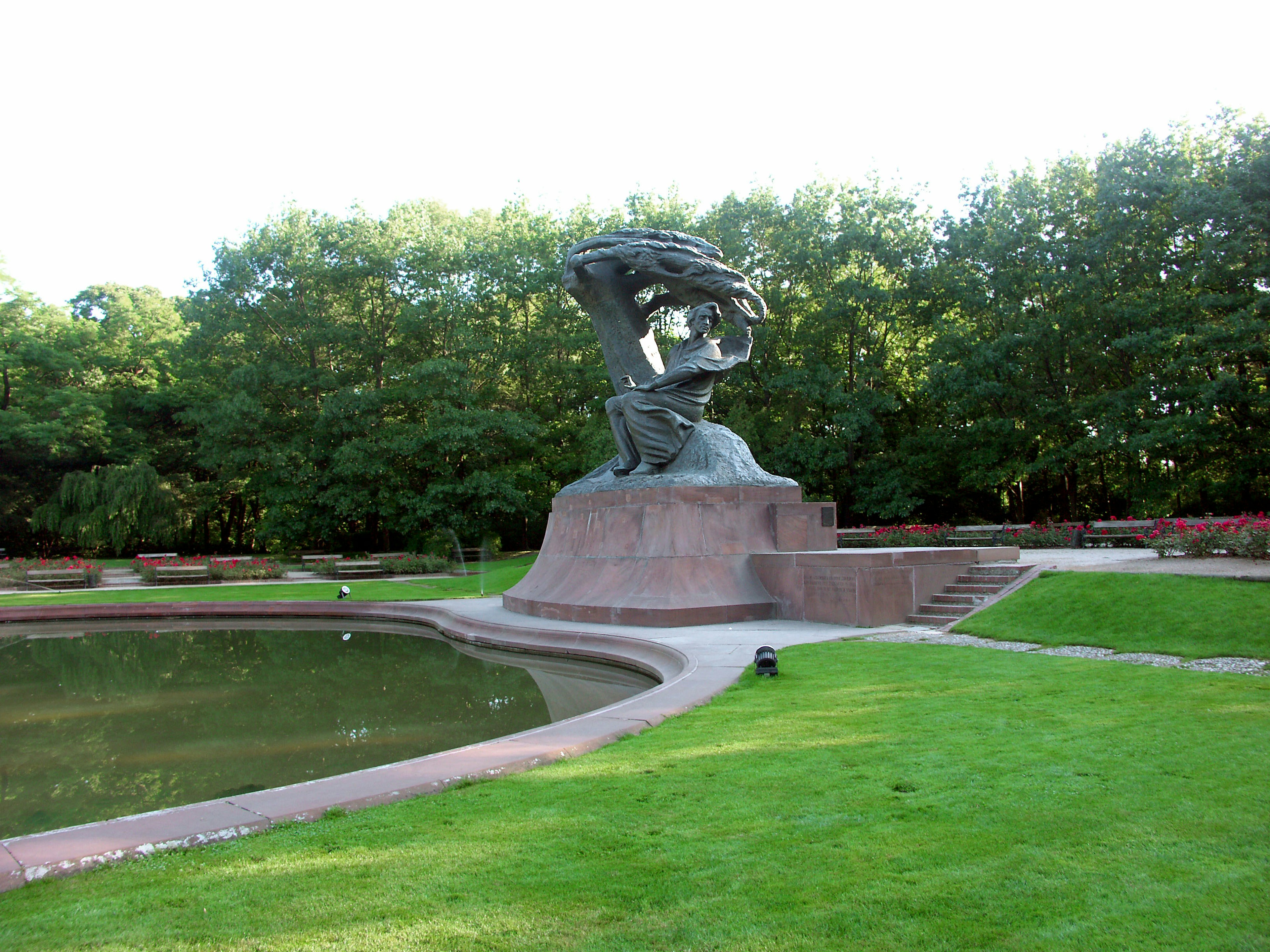 Escultura cerca de un estanque en un parque con árboles verdes