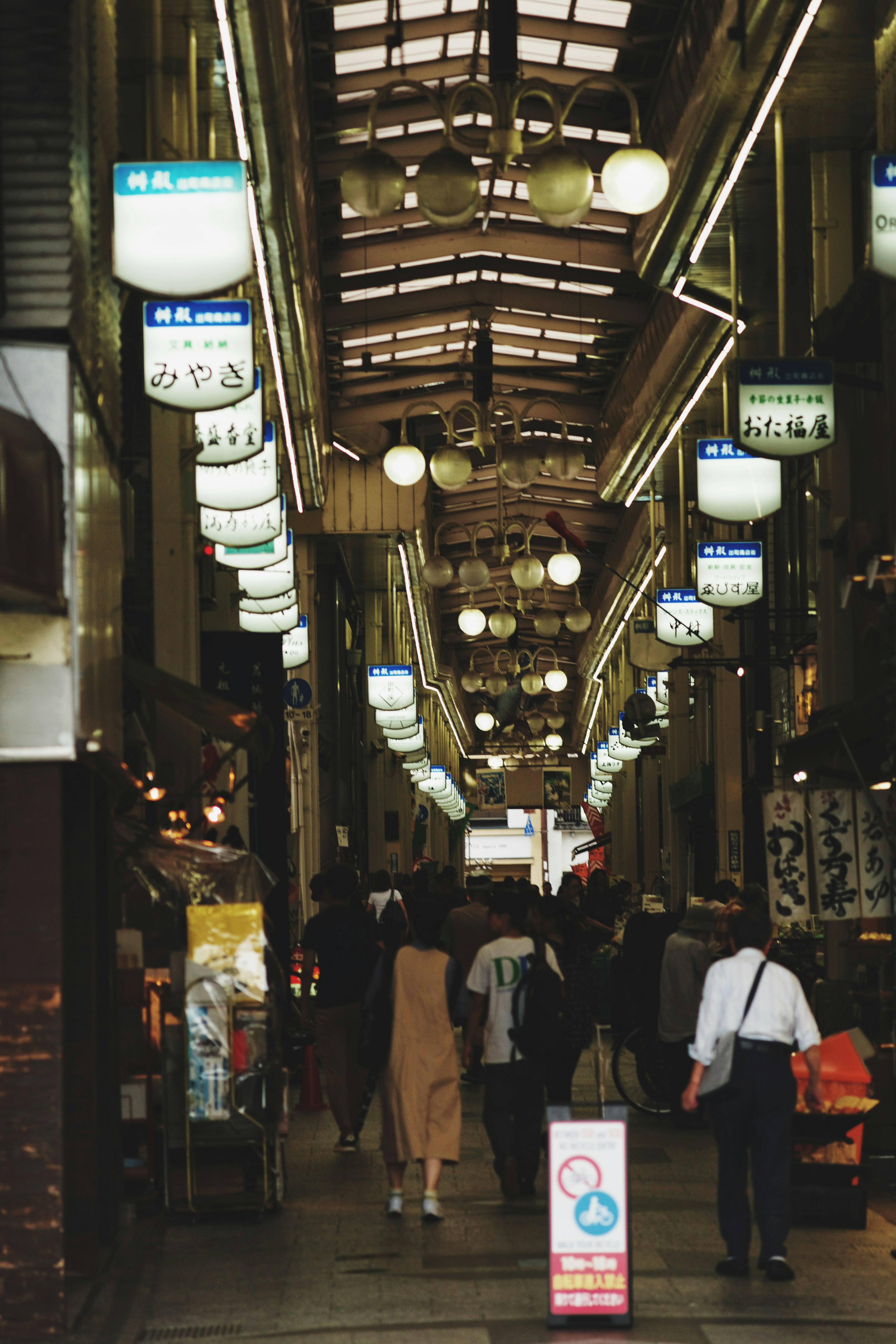 Bustling shopping street with people walking Bright lights and signs are prominent