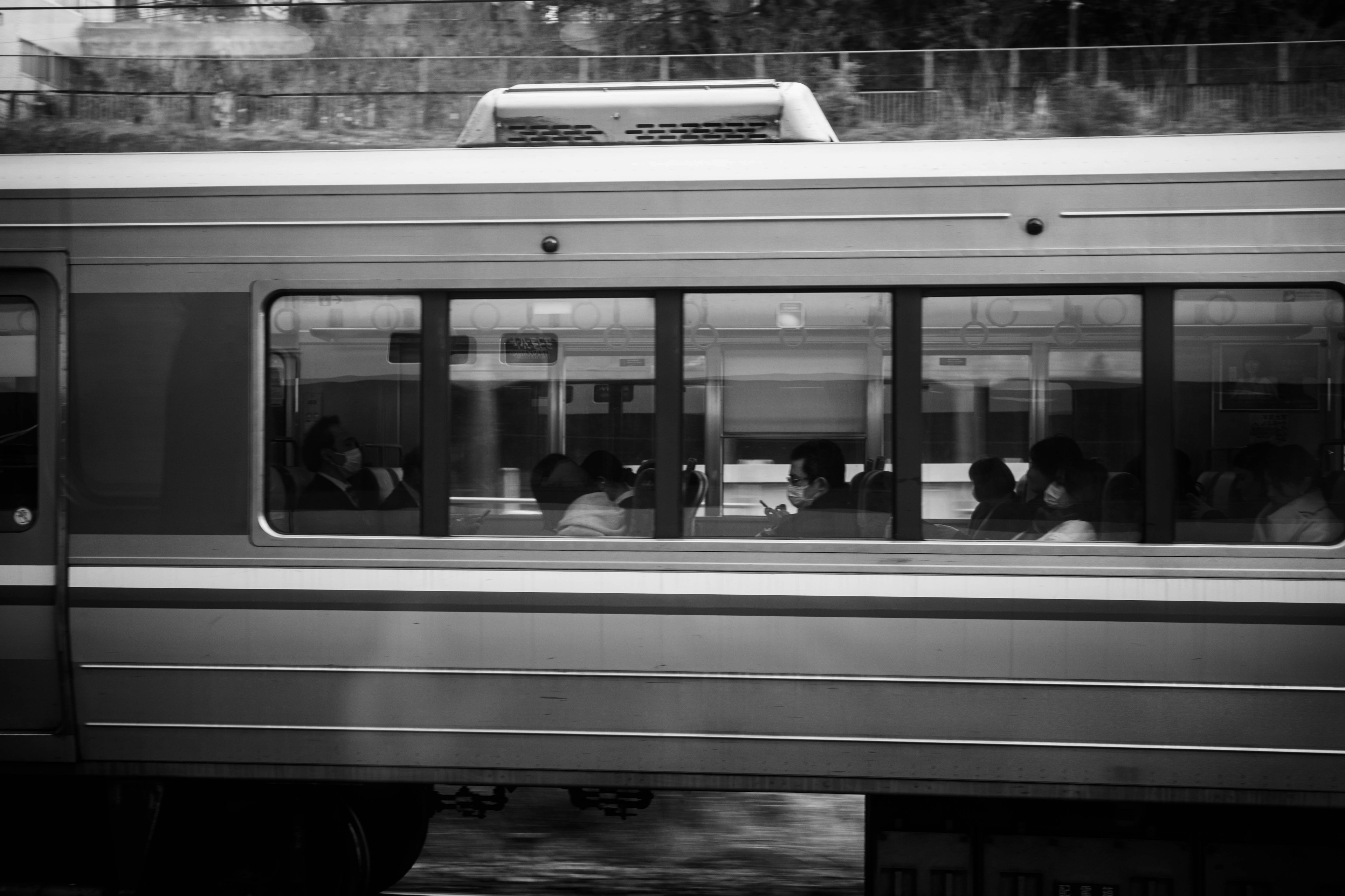 Imagen en blanco y negro de pasajeros de tren visibles a través de una ventana