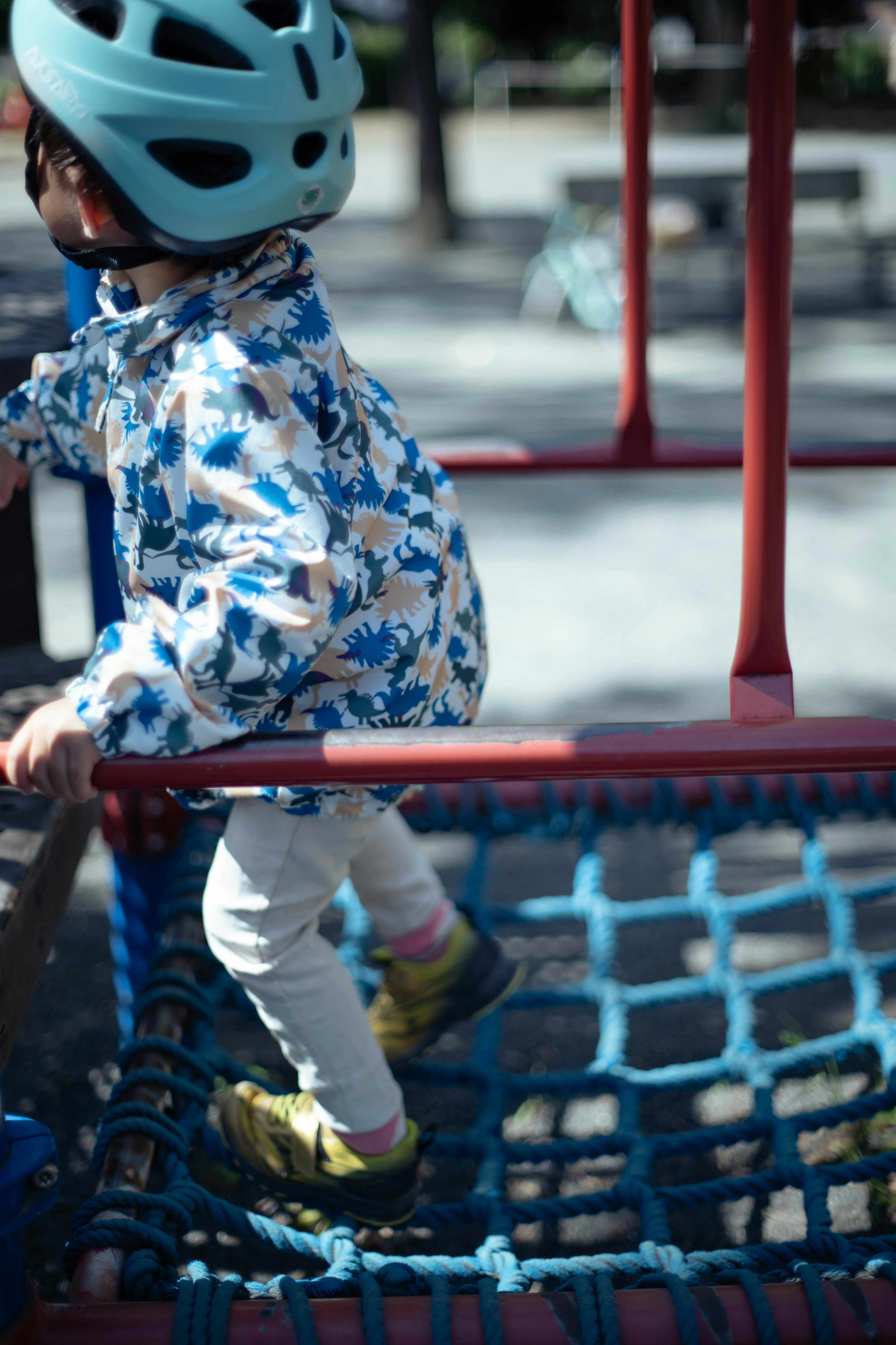 Enfant portant un casque bleu grimpant sur un équipement de jeu dans un parc