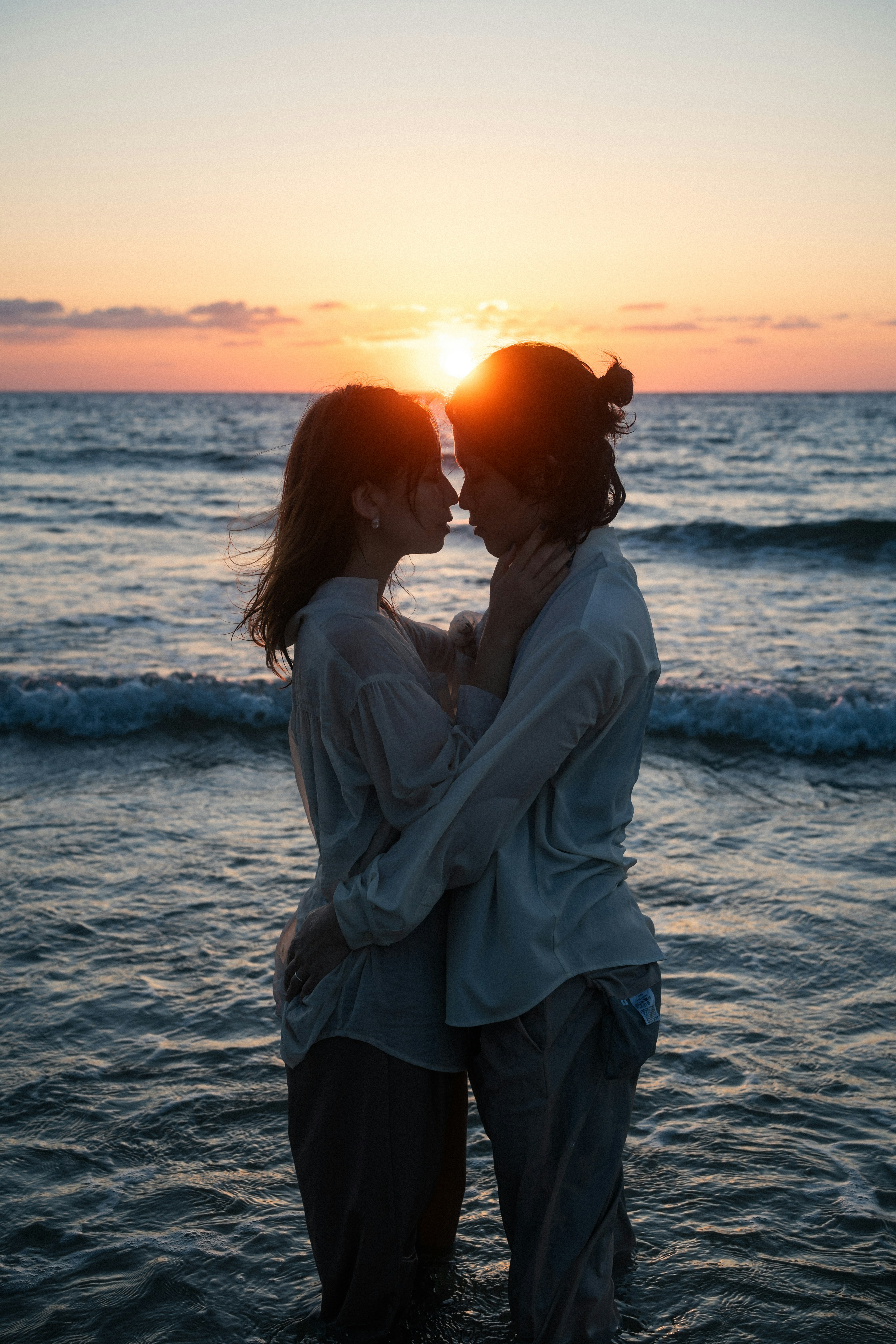 夕日を背景に海で抱き合う二人のシルエット