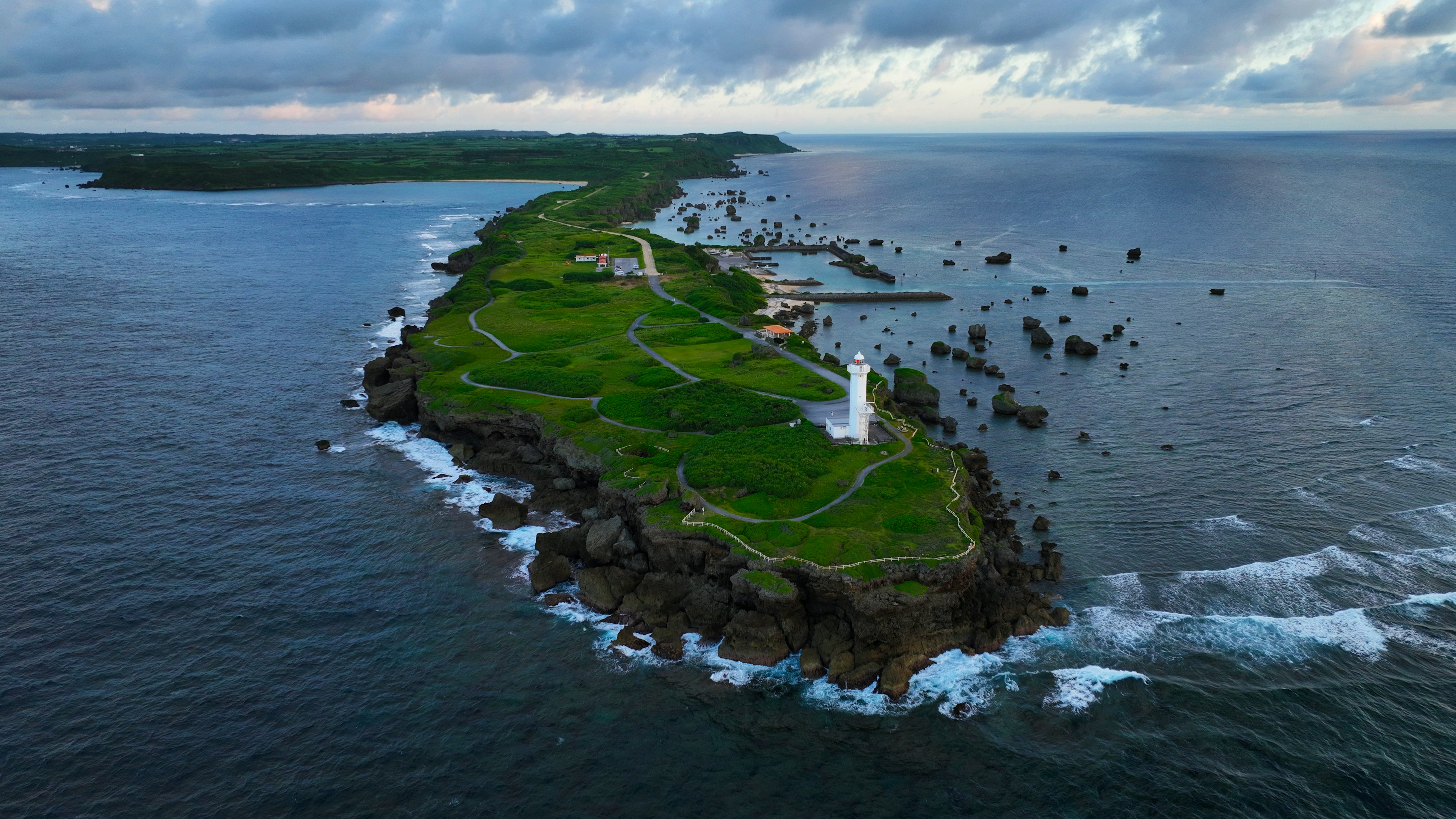 Aerial view of a green island with lighthouses surrounded by ocean