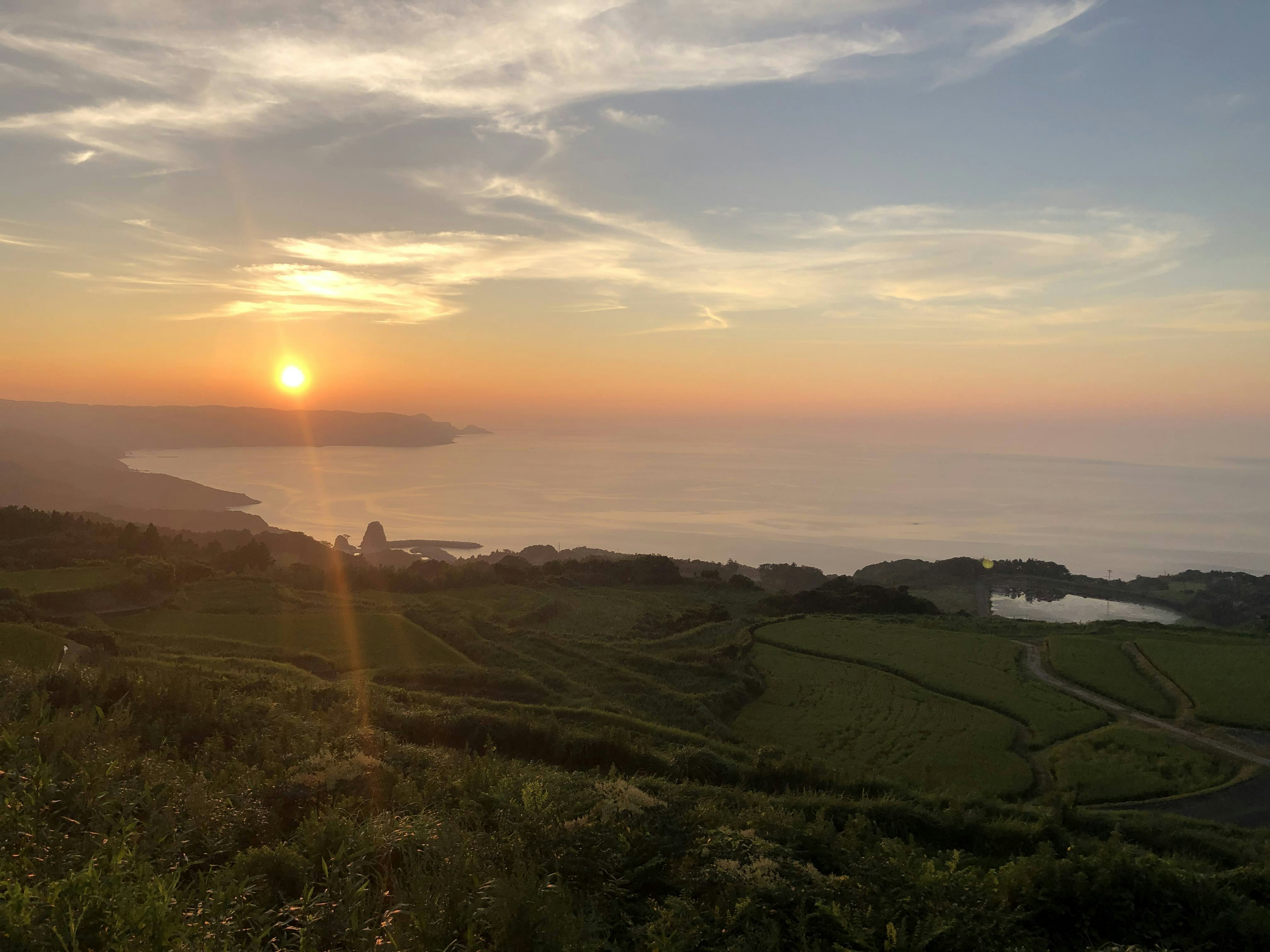 Hermoso paisaje de mar y atardecer con colinas verdes y cielo azul