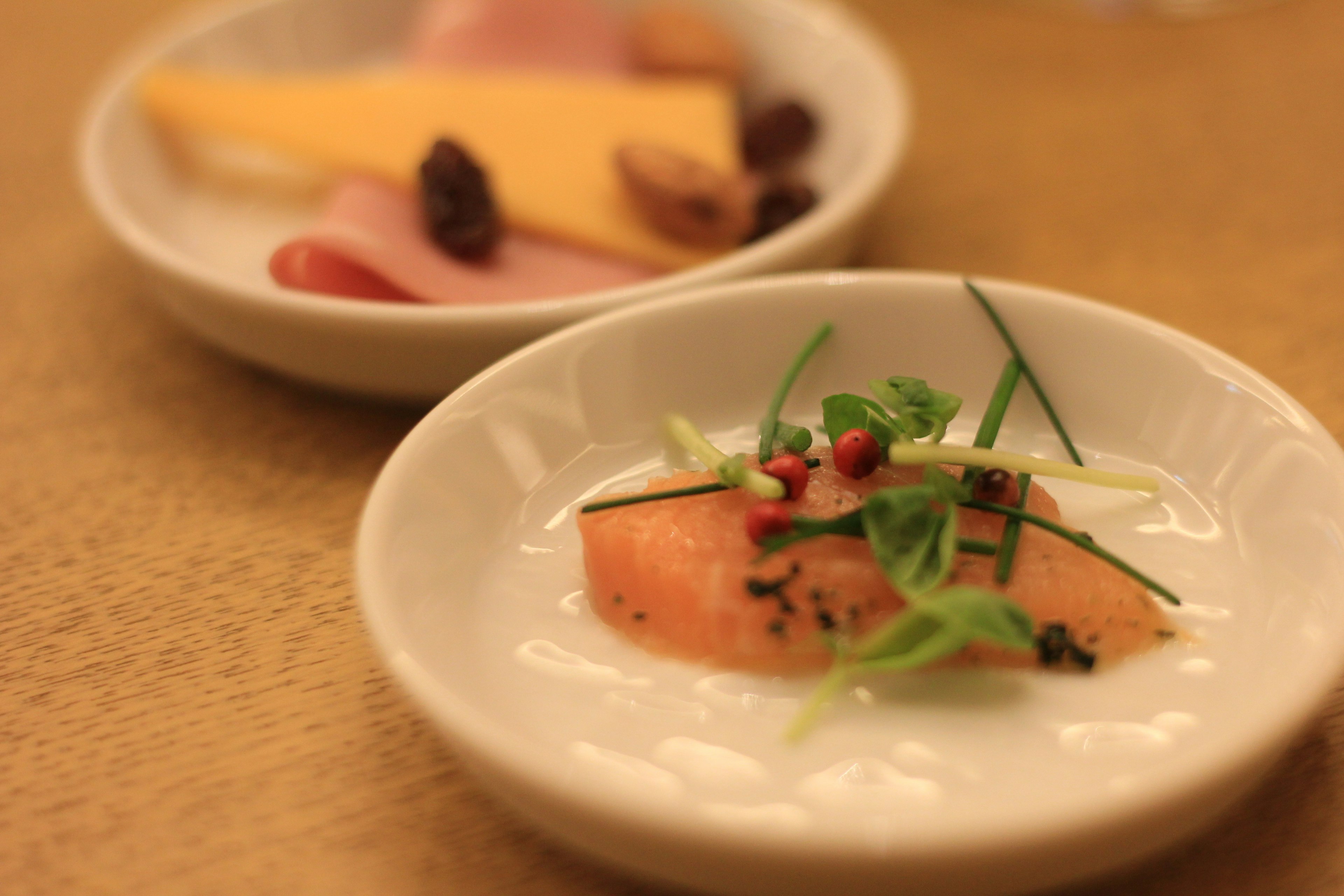 A beautifully plated salmon appetizer with a side of cheese and ham