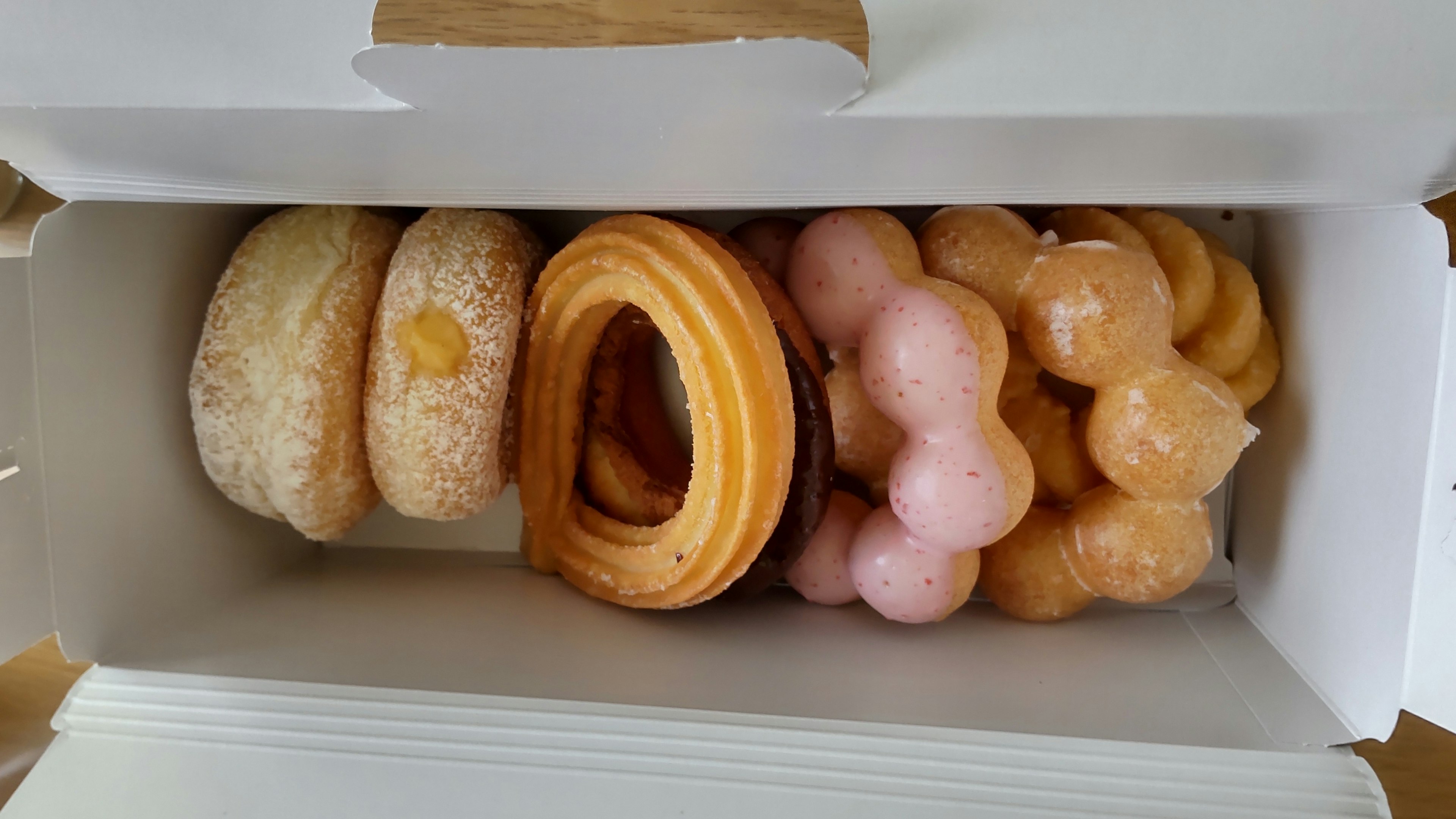 A variety of donuts and pastries arranged in a box