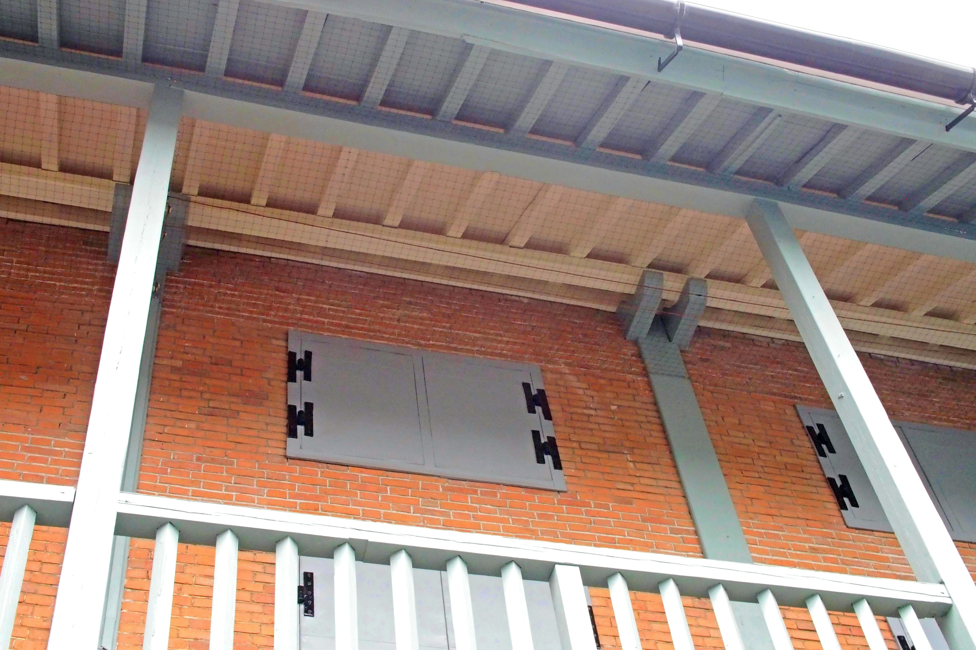 Exterior view of a building featuring a wooden balcony and red brick wall