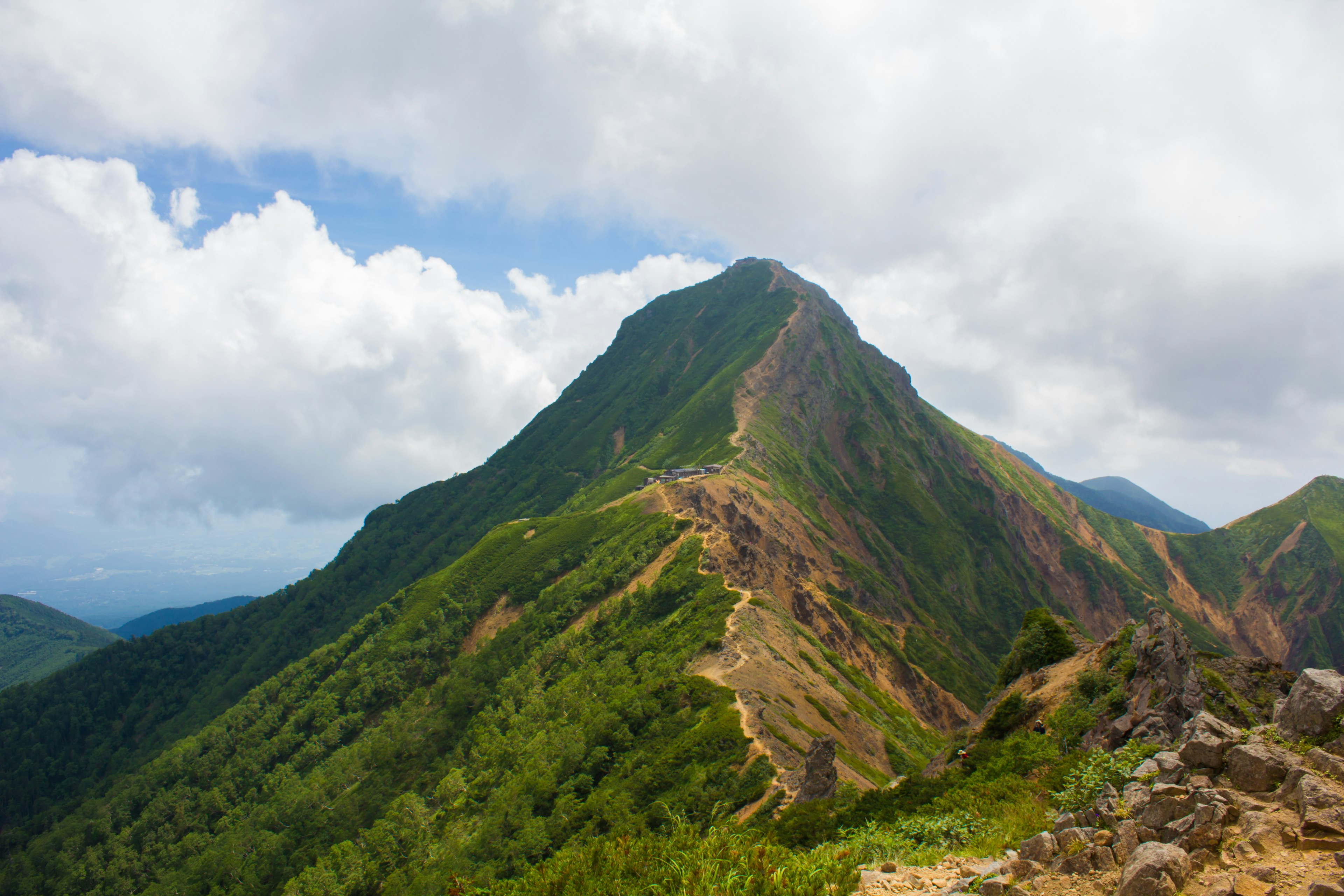 緑の山々と青空を背景にした険しい山の風景