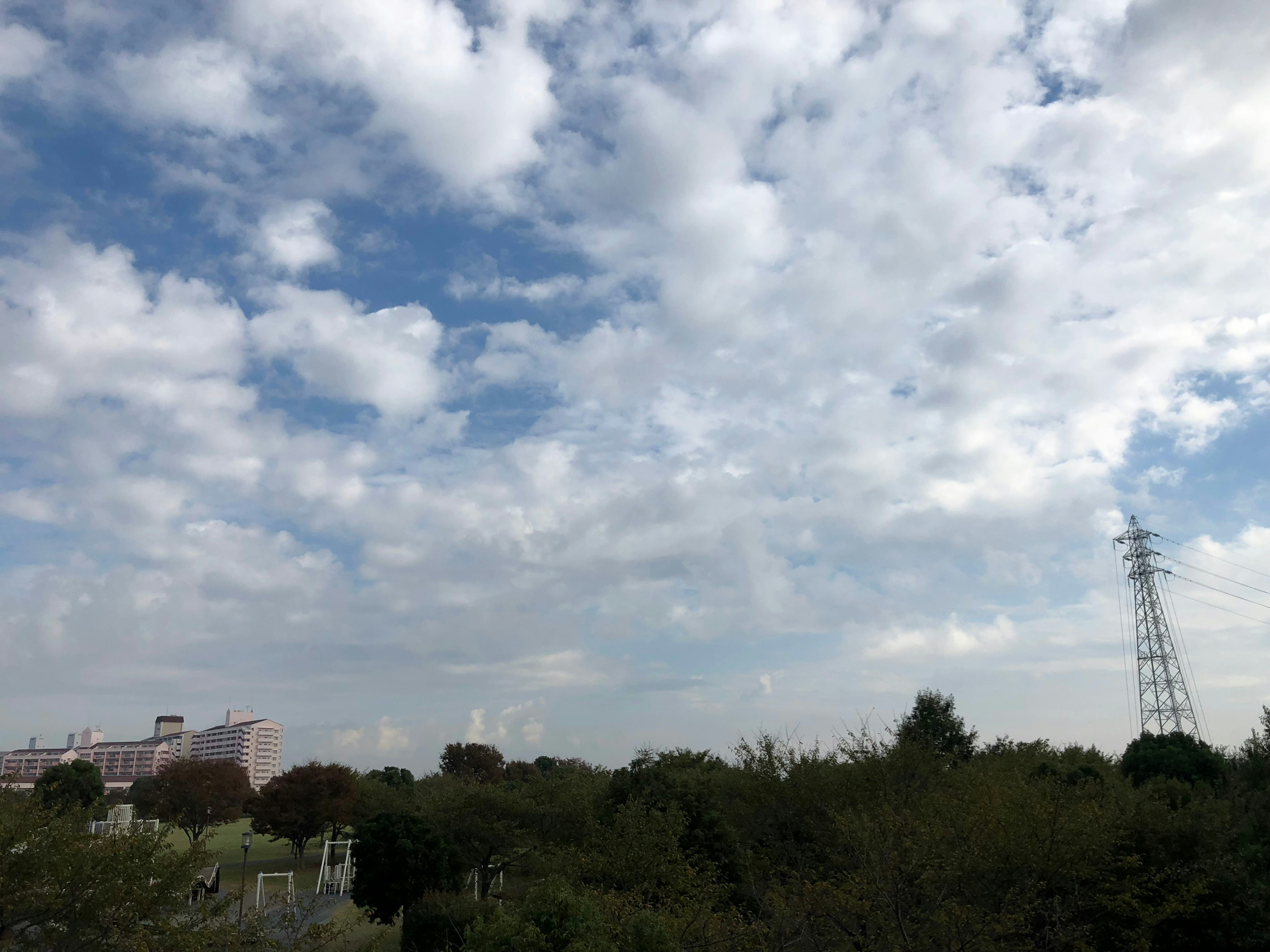 Pemandangan dengan langit biru awan putih vegetasi subur dan saluran listrik