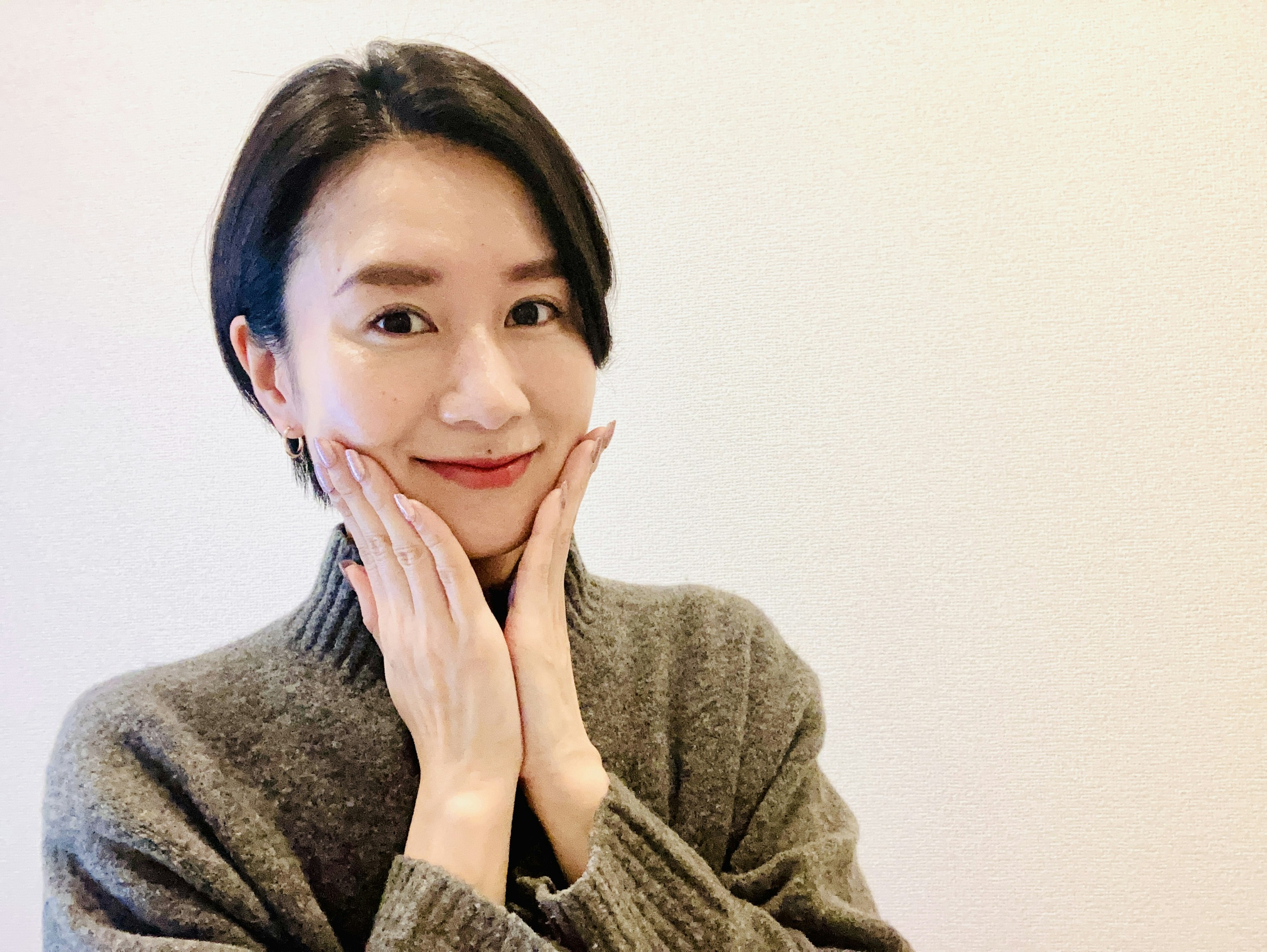 Young woman smiling while cupping her face with her hands