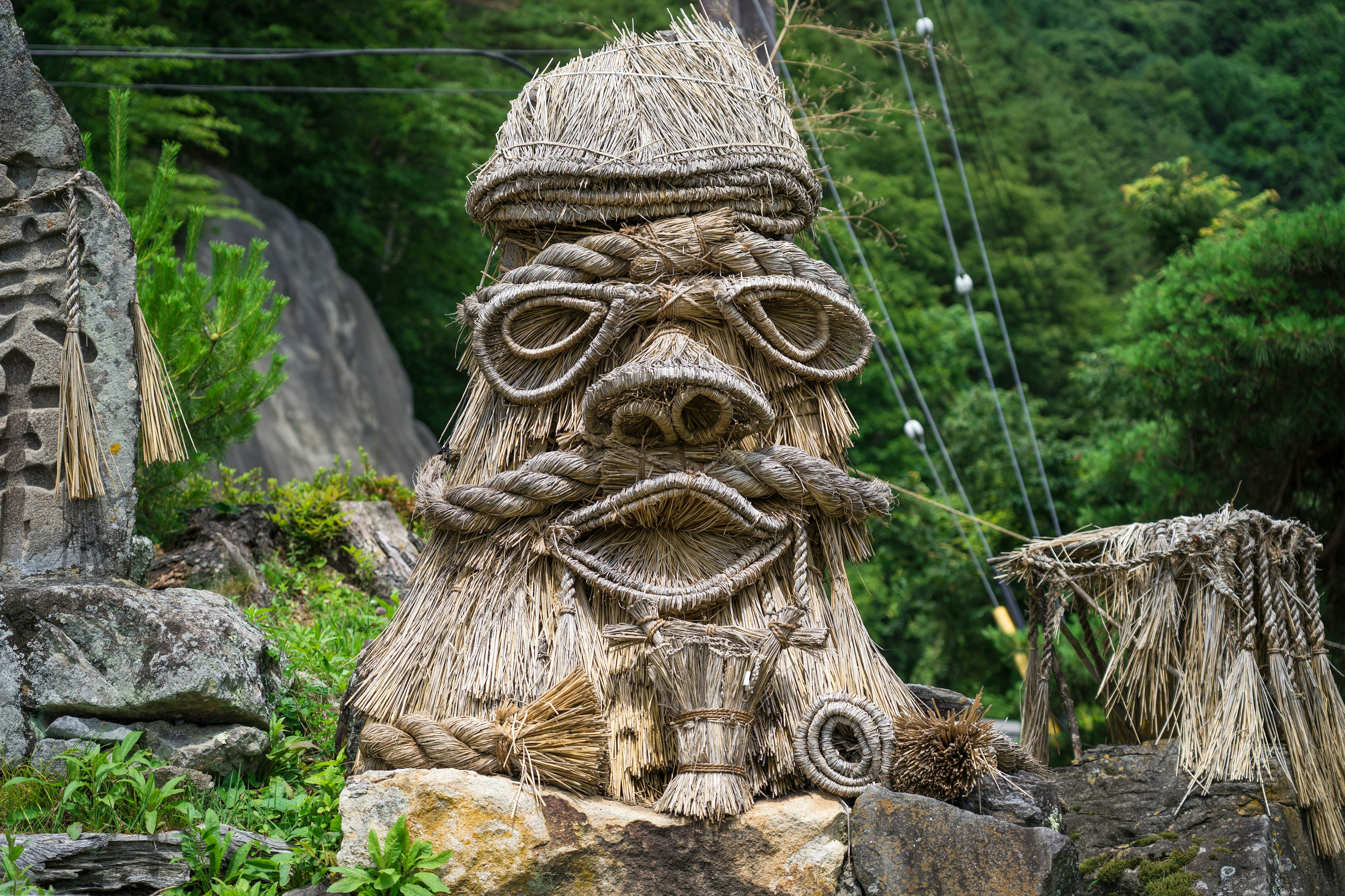 Large straw sculpture of a face in a mountainous landscape