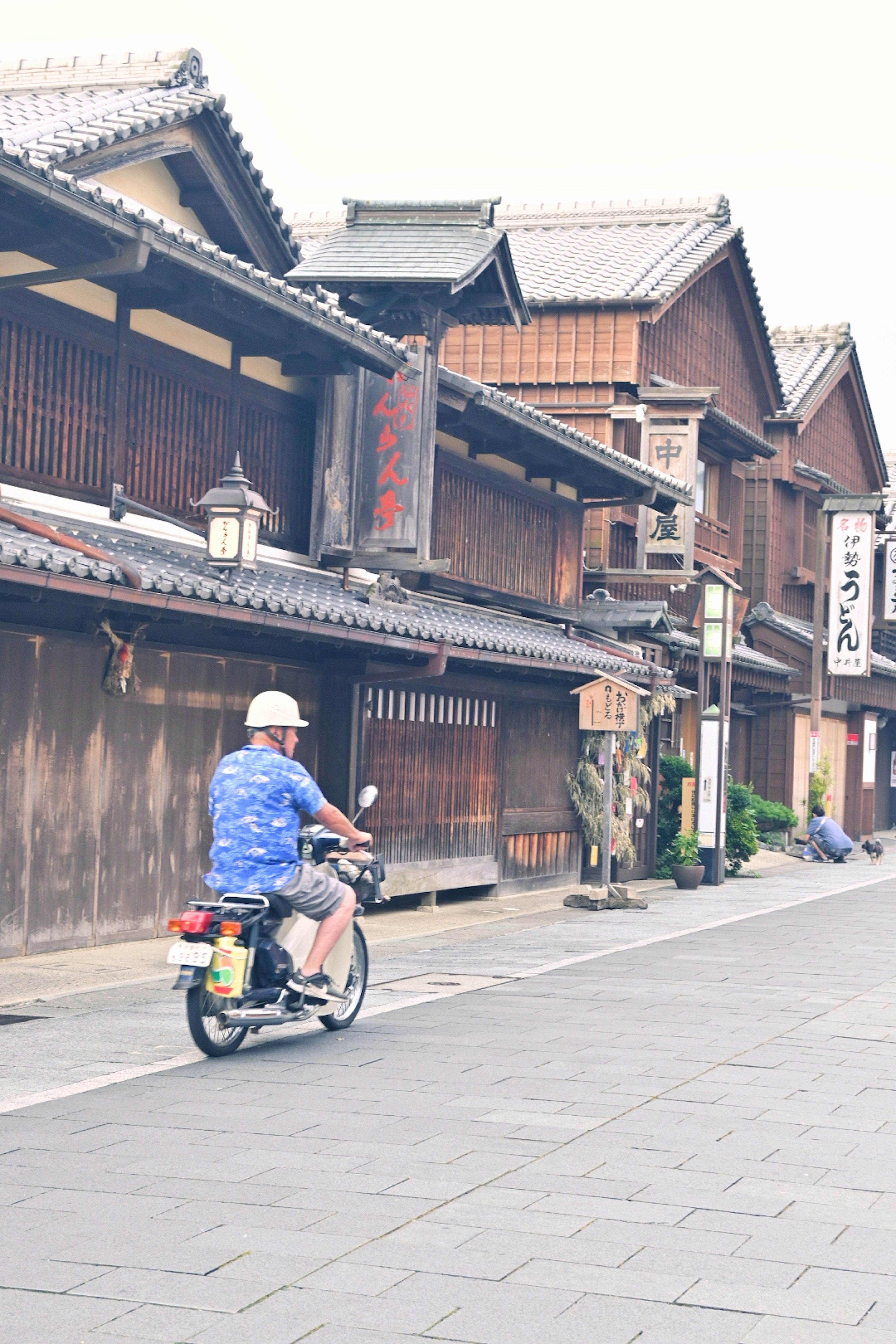 Homme à scooter devant des bâtiments en bois traditionnels japonais