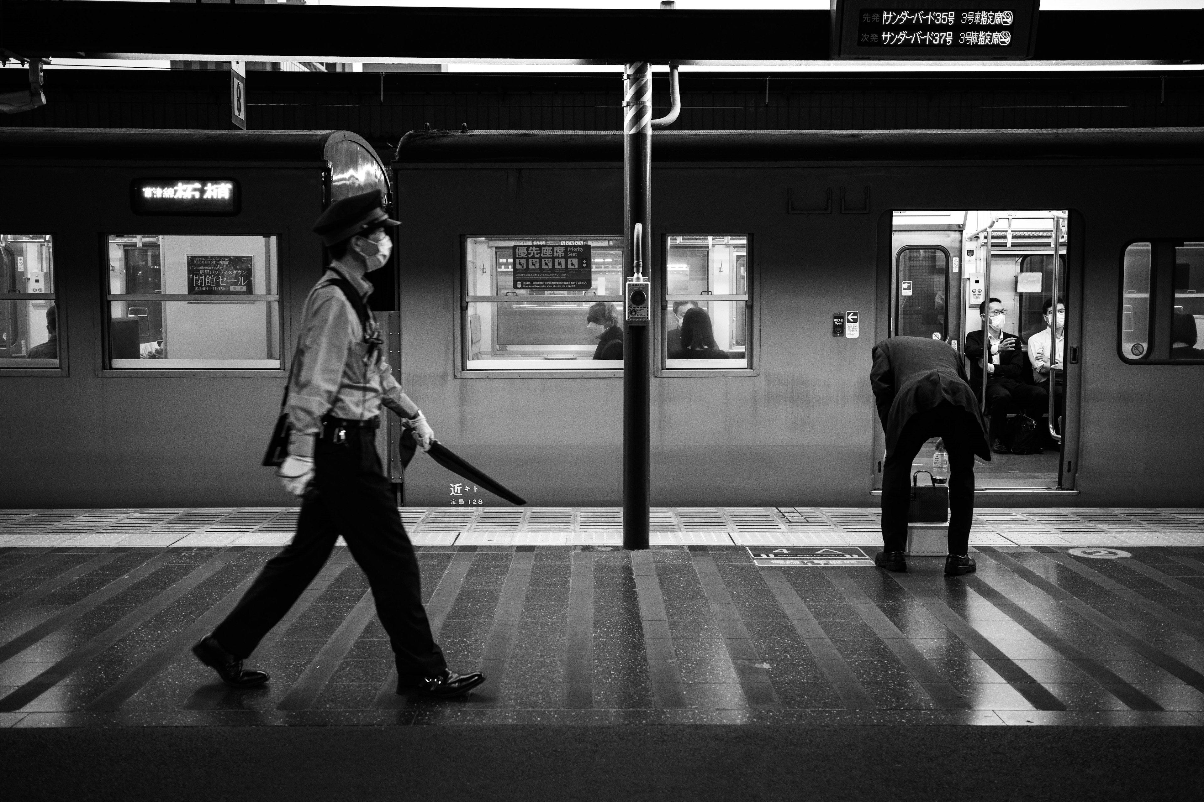 A police officer walking on a train platform with a passenger boarding