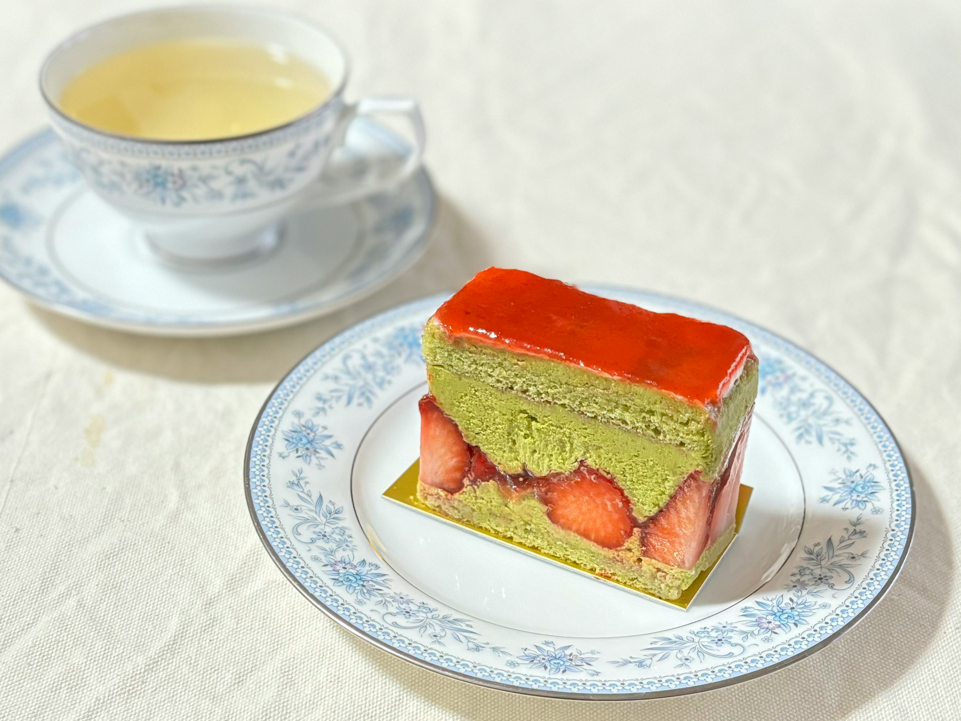 緑茶ケーキとイチゴの層があるデザートとカップの紅茶