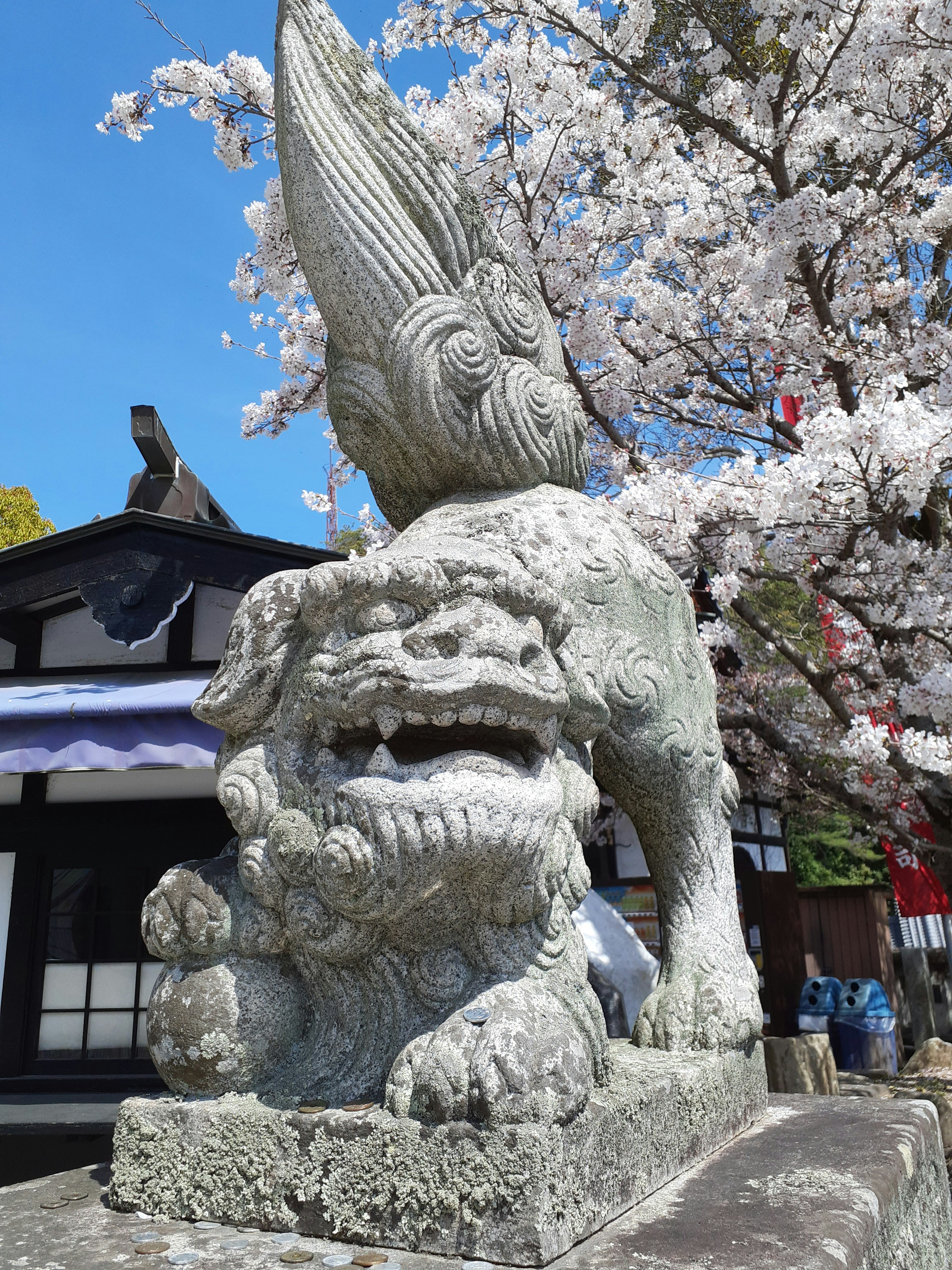 Stone lion statue with a winged figure beside cherry blossom trees