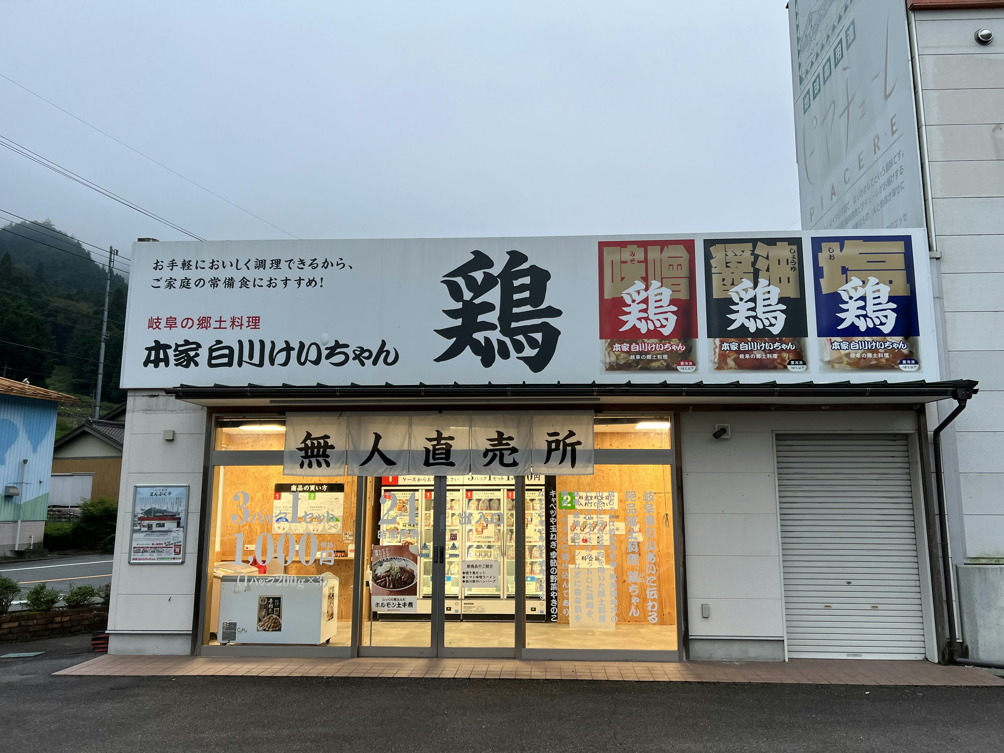 Façade blanche d'une boutique de poulet avec de grands panneaux et fenêtres