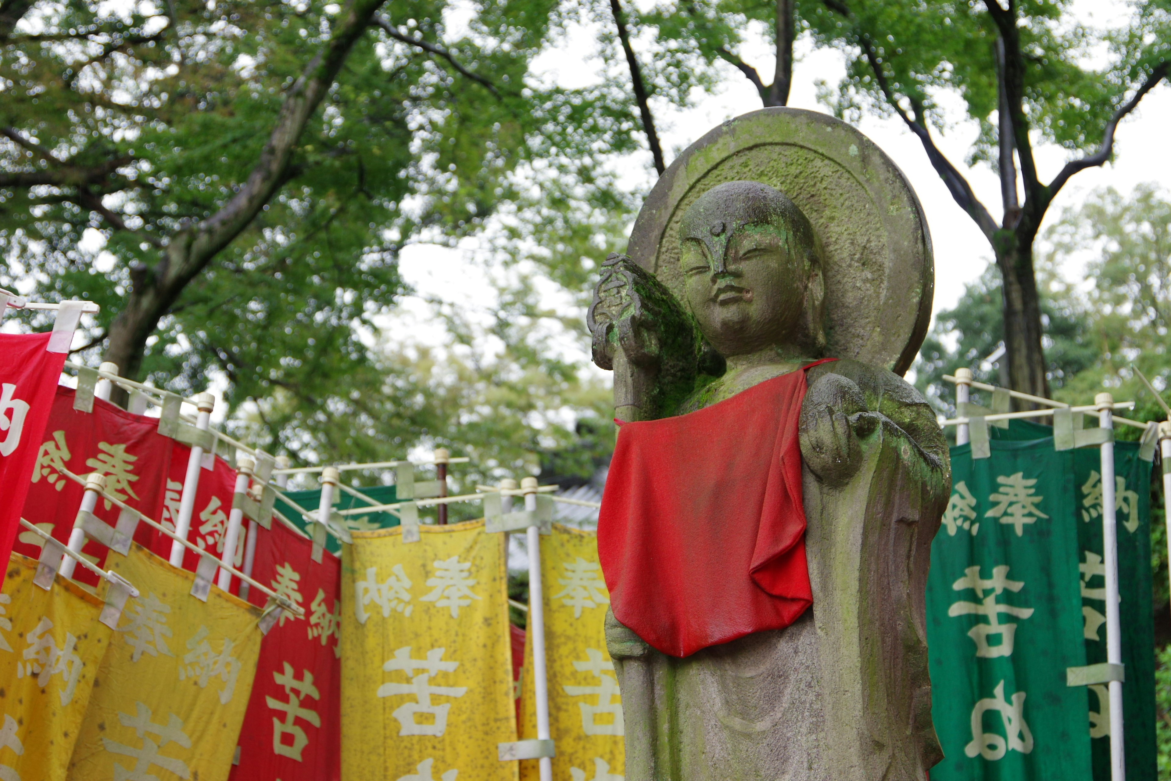 Statua di un Buddha circondata da bandiere colorate in un parco