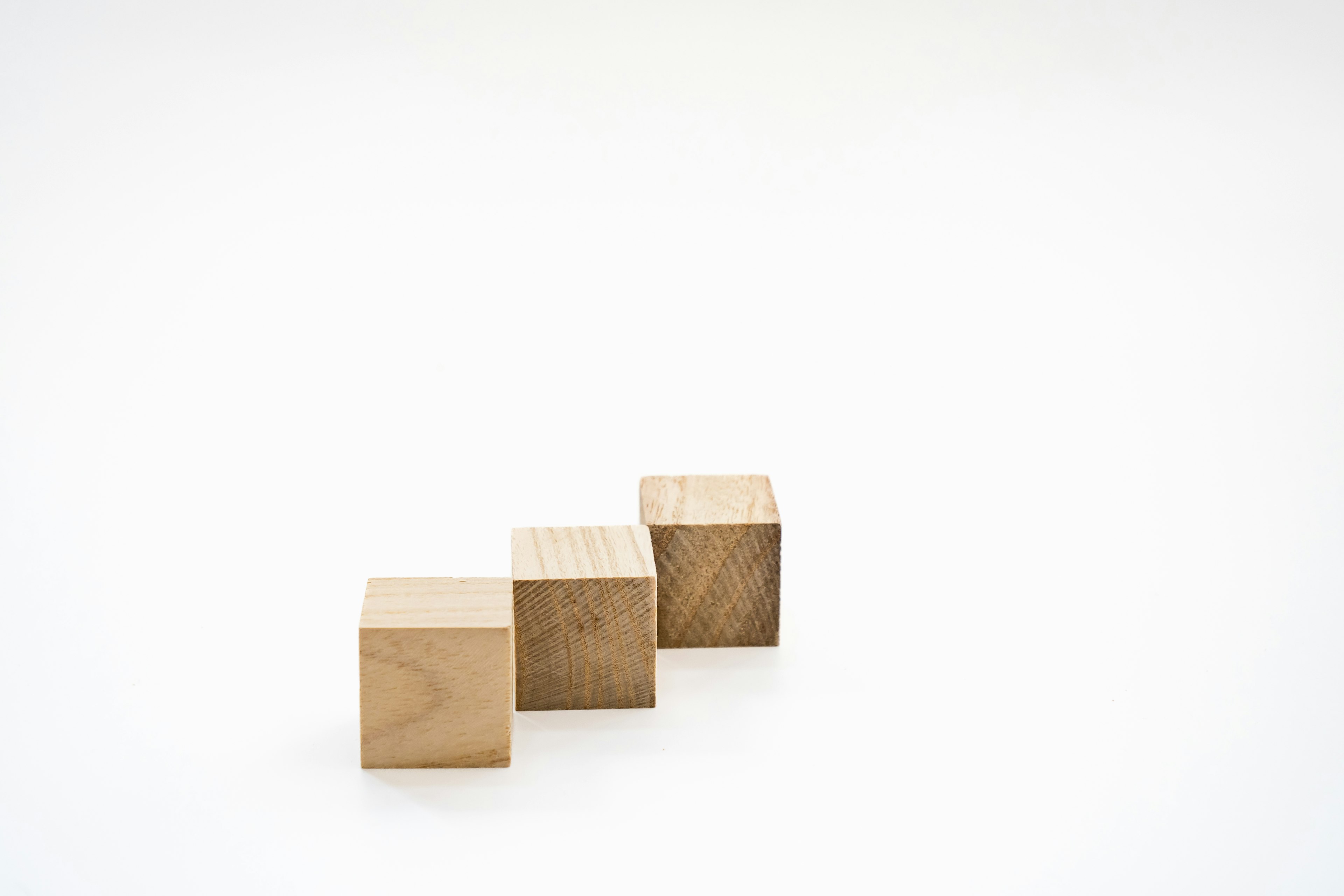 Three wooden cubes arranged in a row on a white background