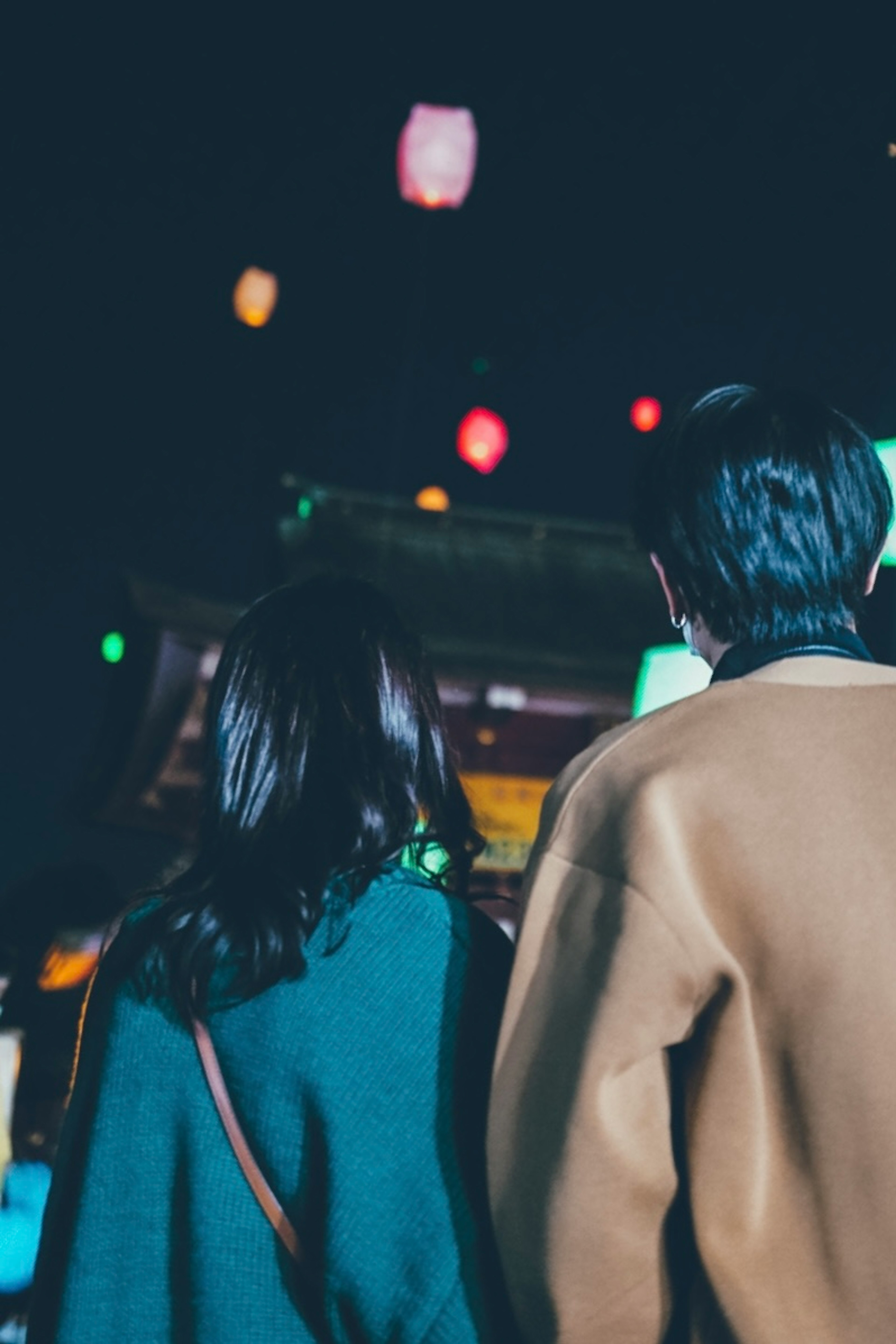 Pareja de pie junta con linternas coloridas brillando en la noche