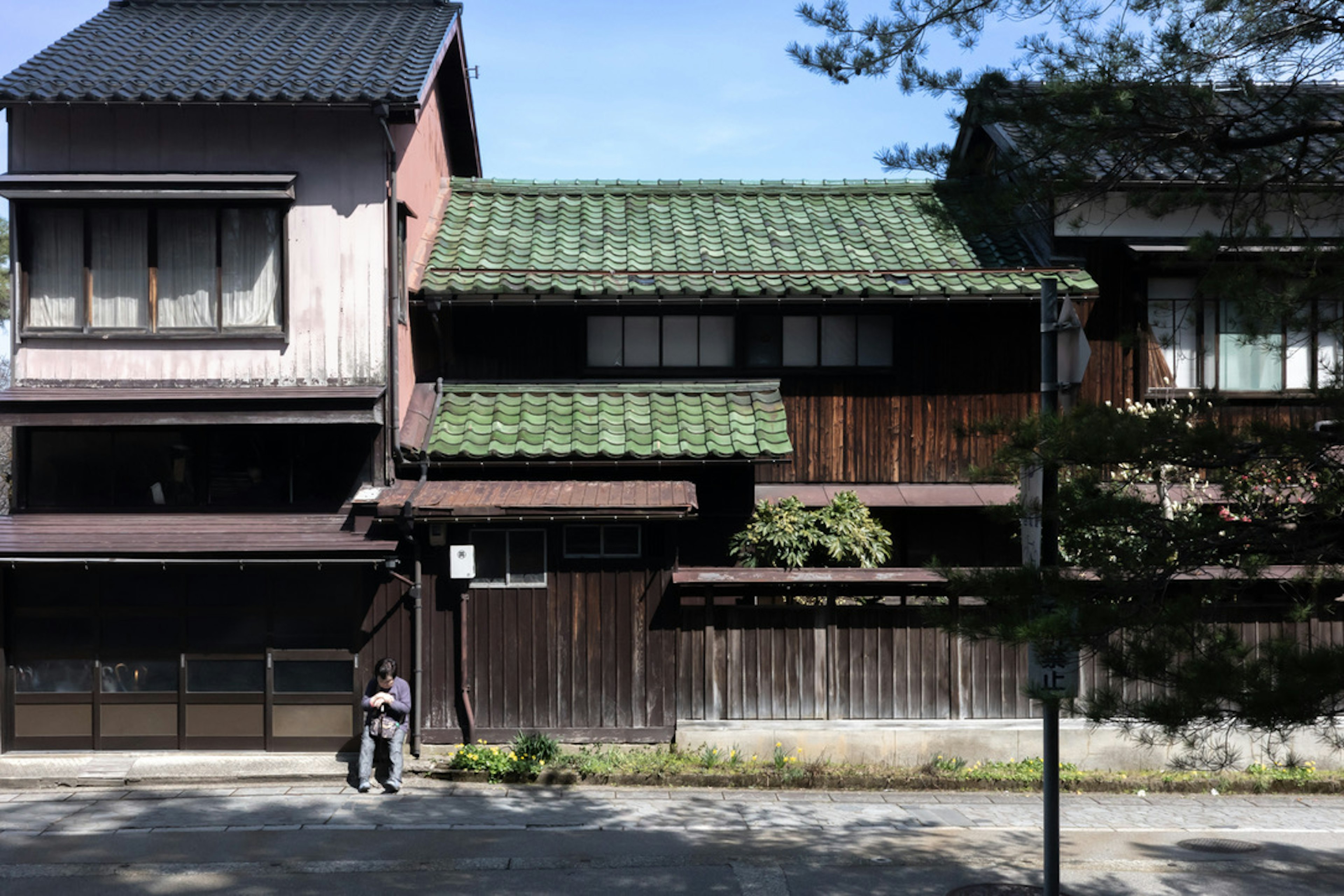 伝統的な日本の家屋の外観、緑色の瓦屋根と木製の壁、穏やかな通りの風景