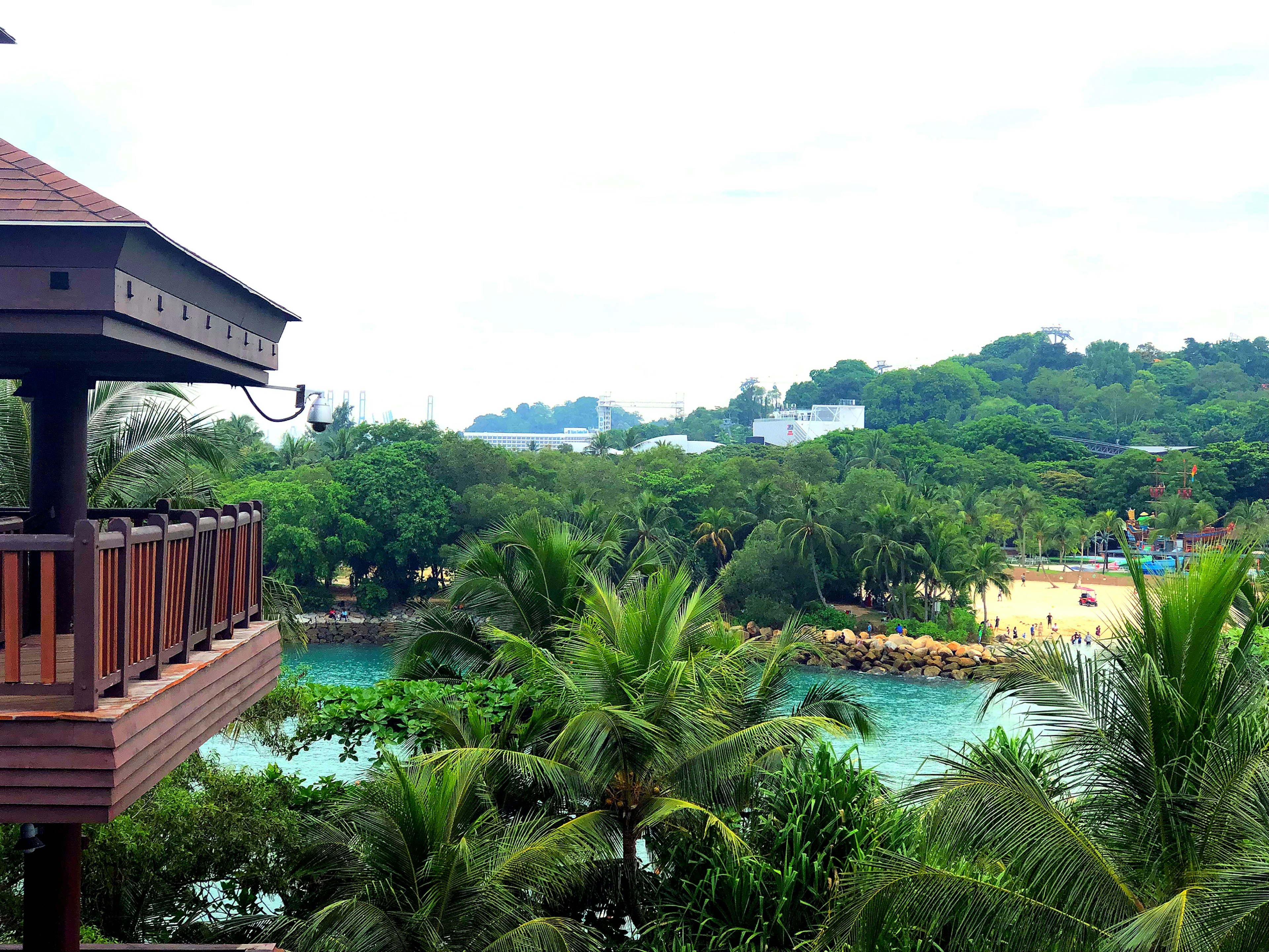 Scenic view from a resort balcony featuring lush greenery and a blue beach