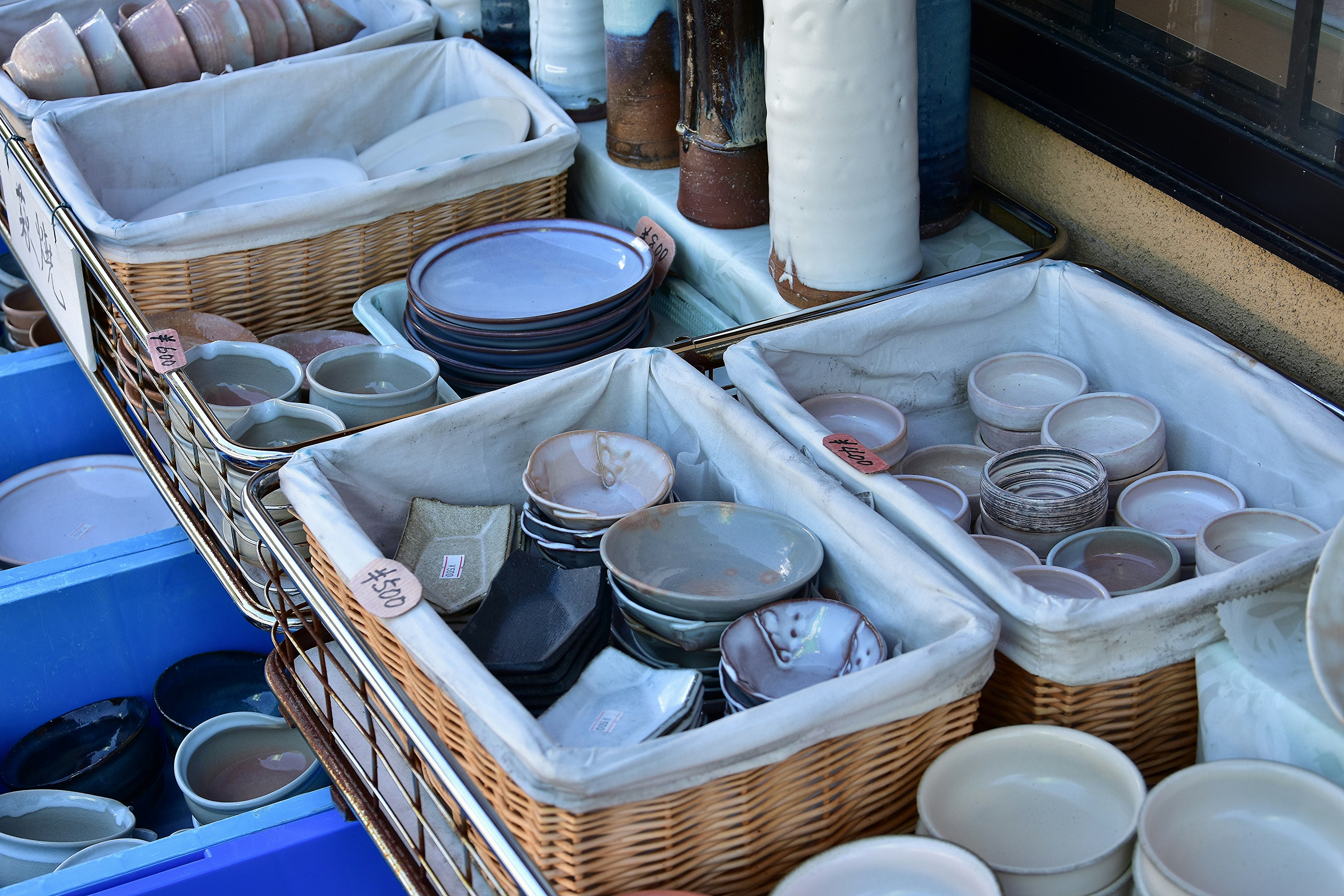 Baskets filled with various pottery bowls and plates displayed outdoors