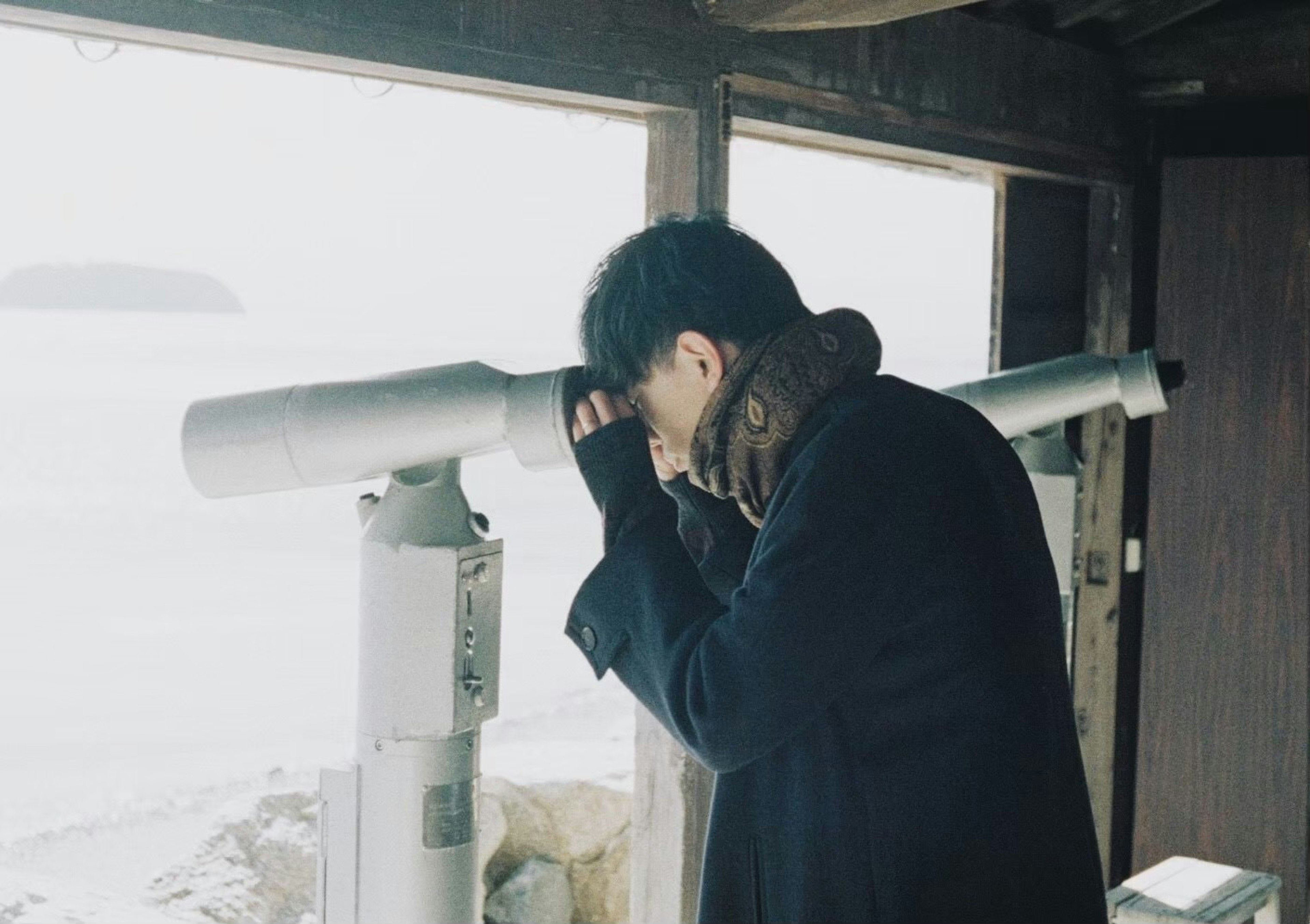 A man looking through a telescope at the sea