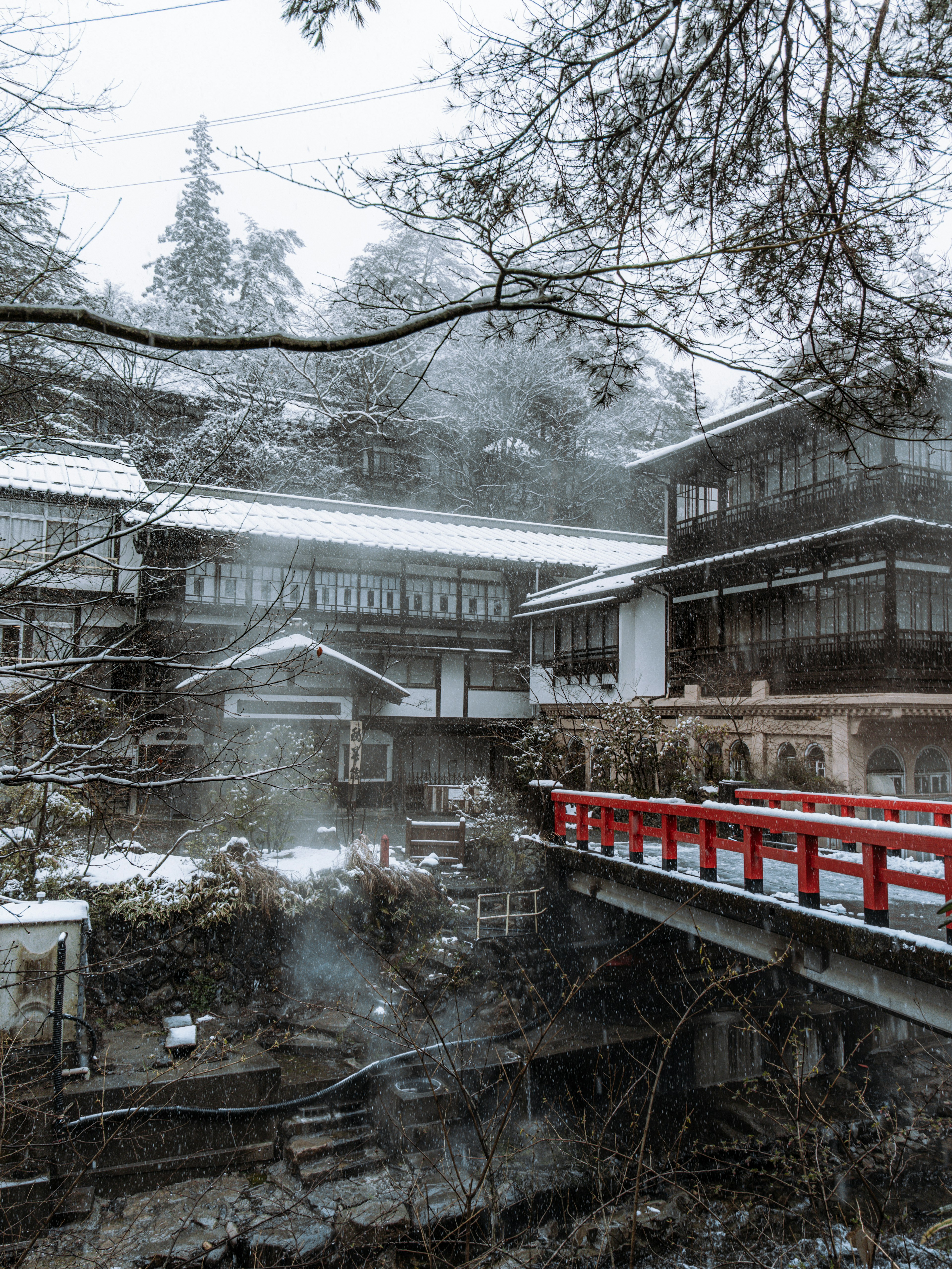 Snow-covered hot spring inn with a red bridge