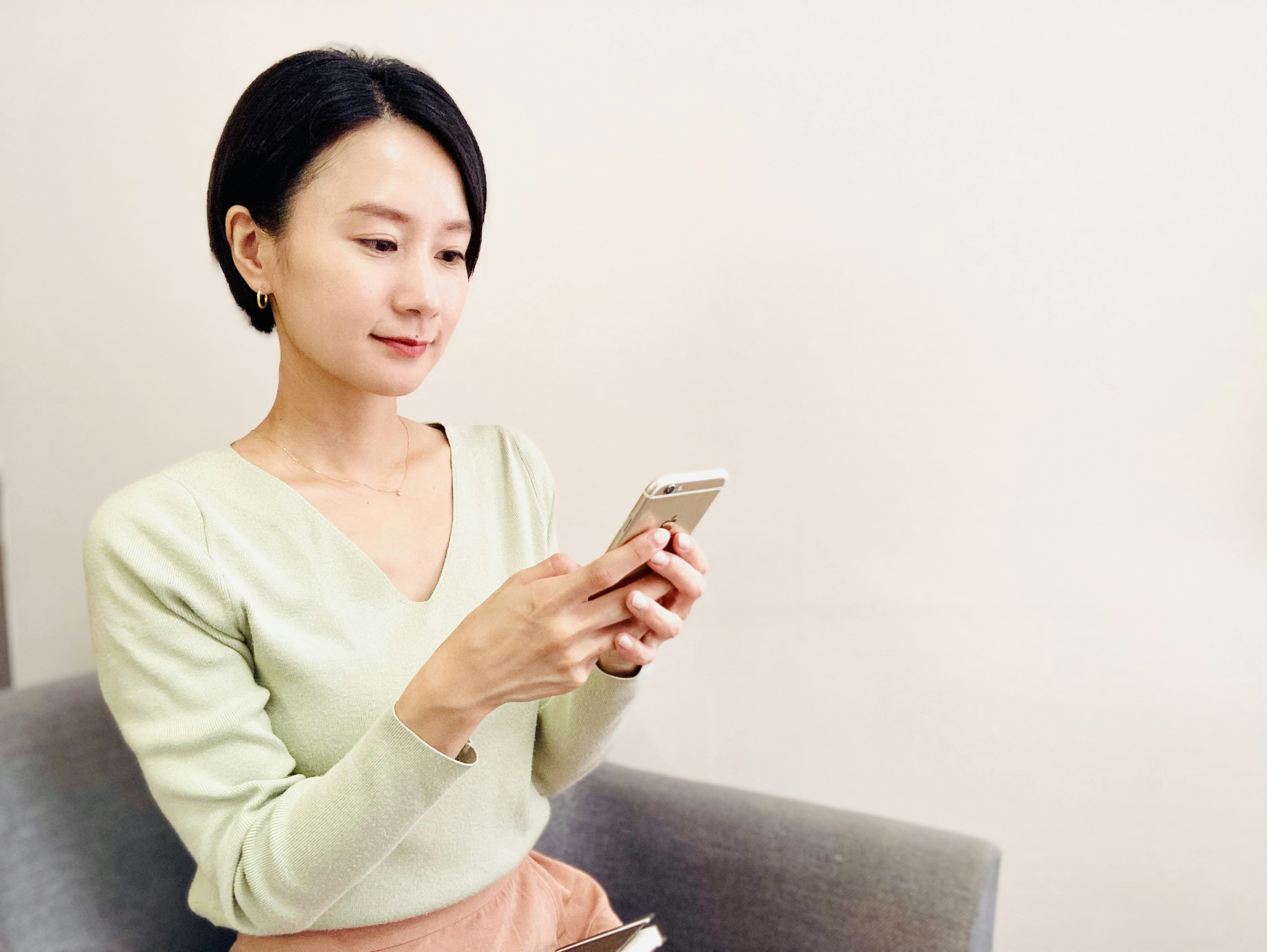 A woman using a smartphone while sitting on a gray chair