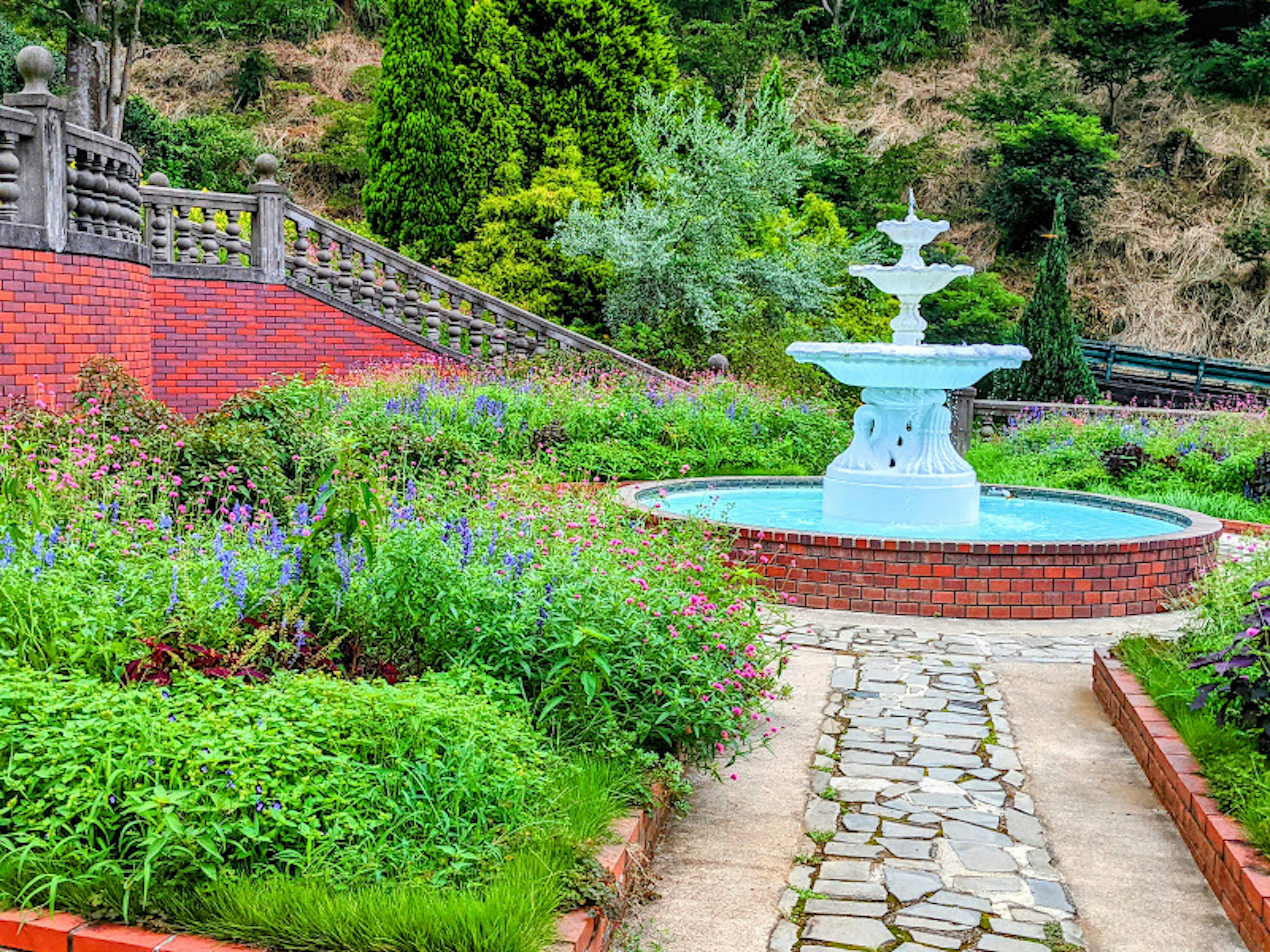 Jardín escénico con una fuente azul rodeada de exuberante vegetación