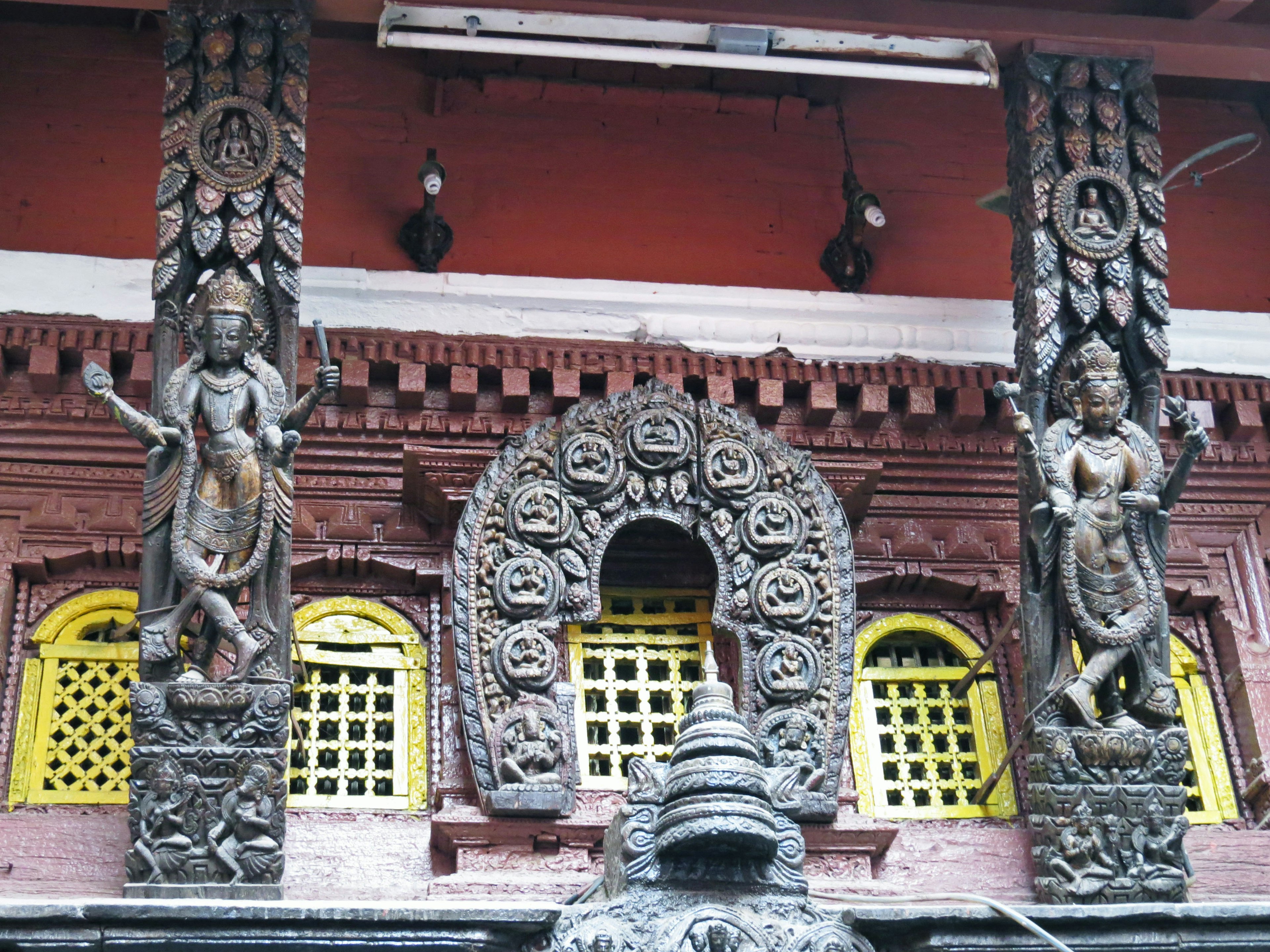 Fachada de un templo con tallas de madera y estatuas con ventanas amarillas