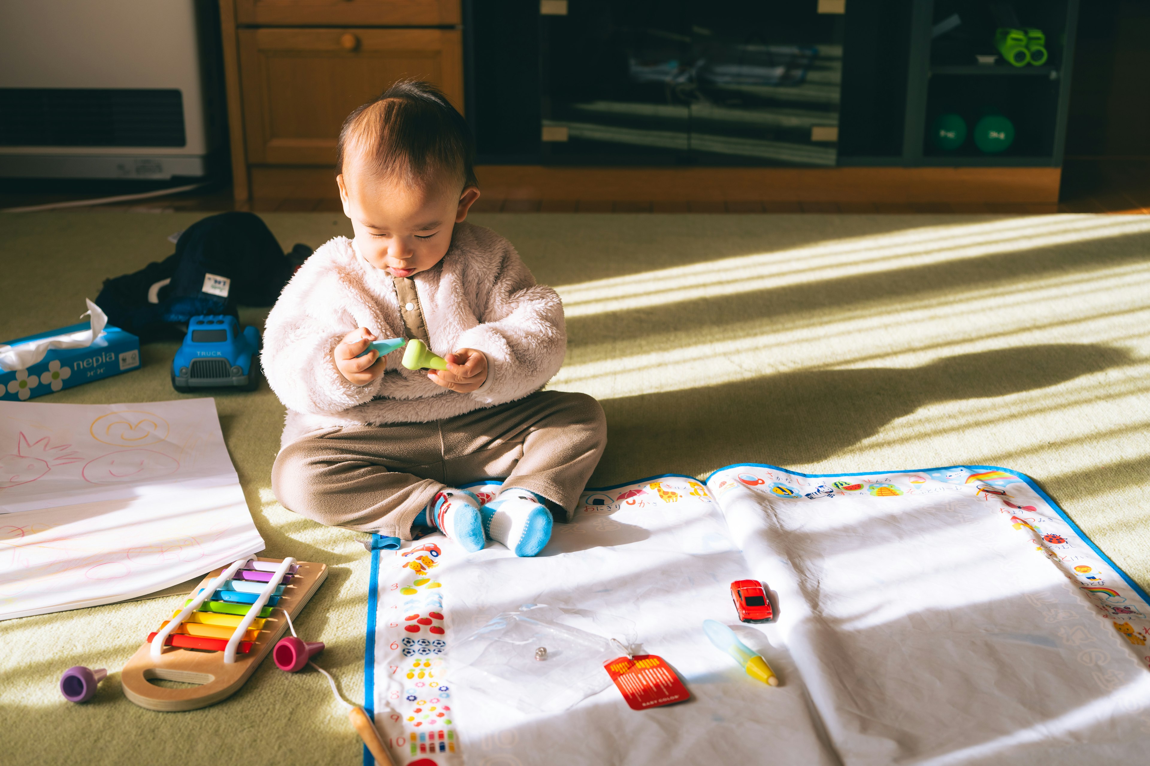 子供がカーペットの上でおもちゃで遊んでいる様子