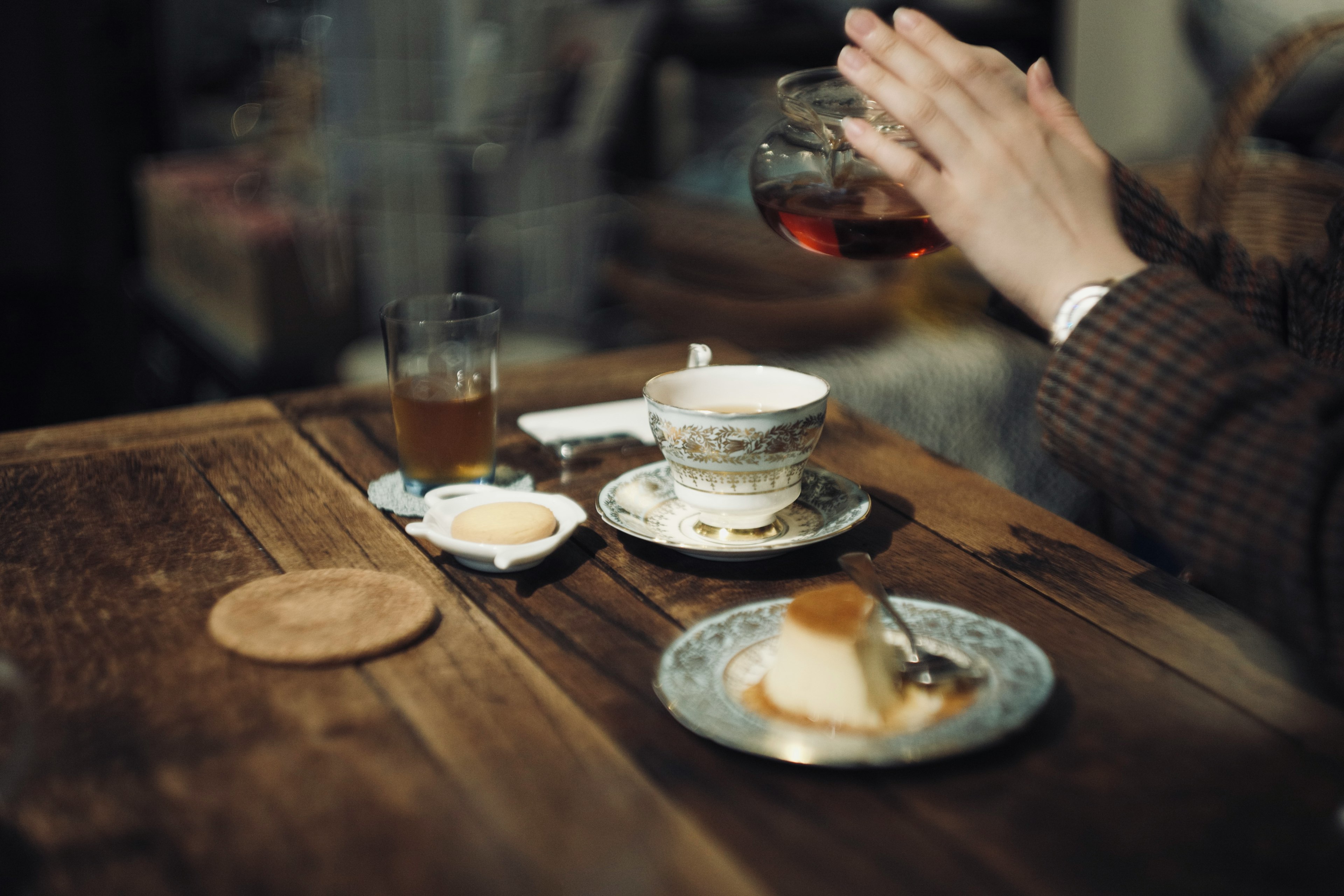 Una mesa con tazas de té y platos de postre Una mano sirviendo té en una taza