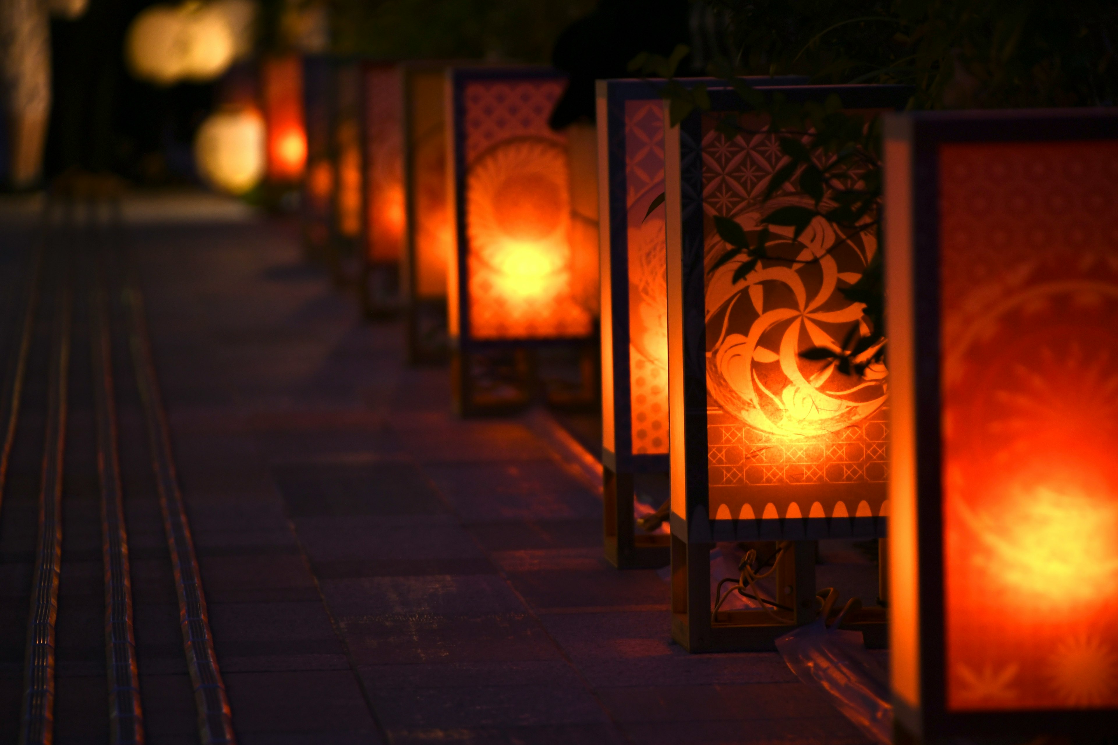 Warm glowing lanterns lined along a nighttime path