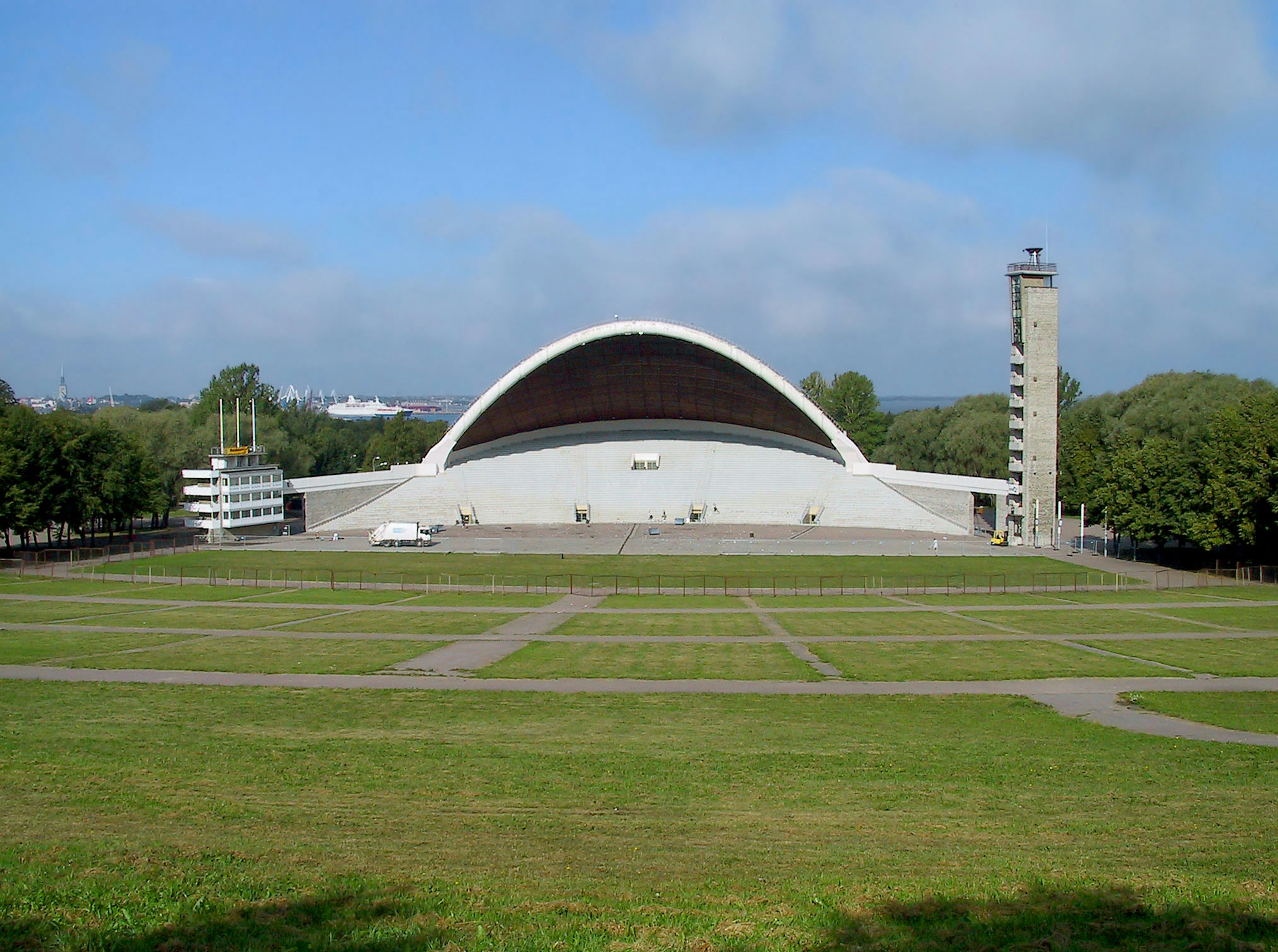 Salle de concert en plein air moderne avec un toit courbé et une tour dans un paysage verdoyant