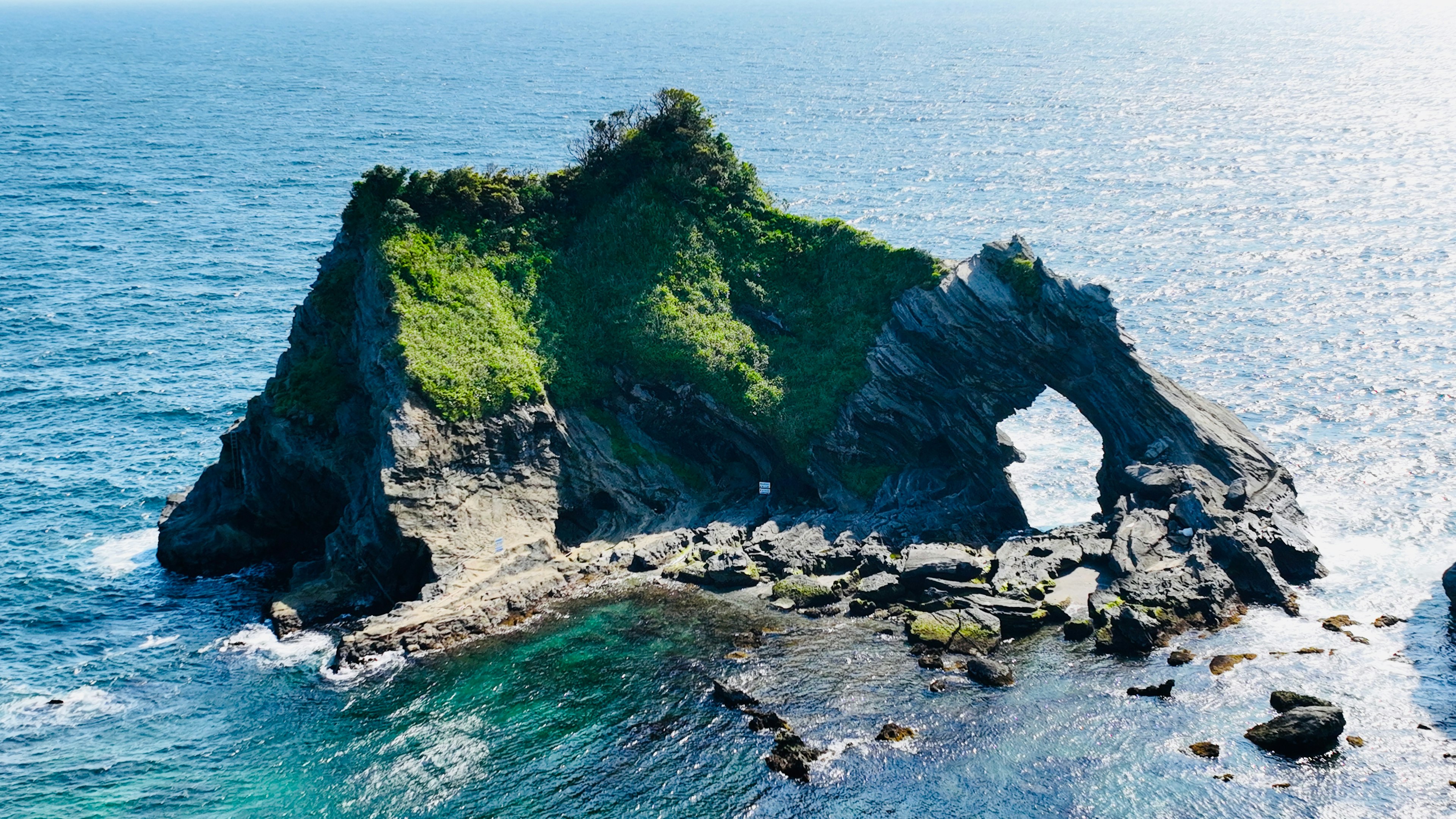 Una isla rocosa verde rodeada de un hermoso océano