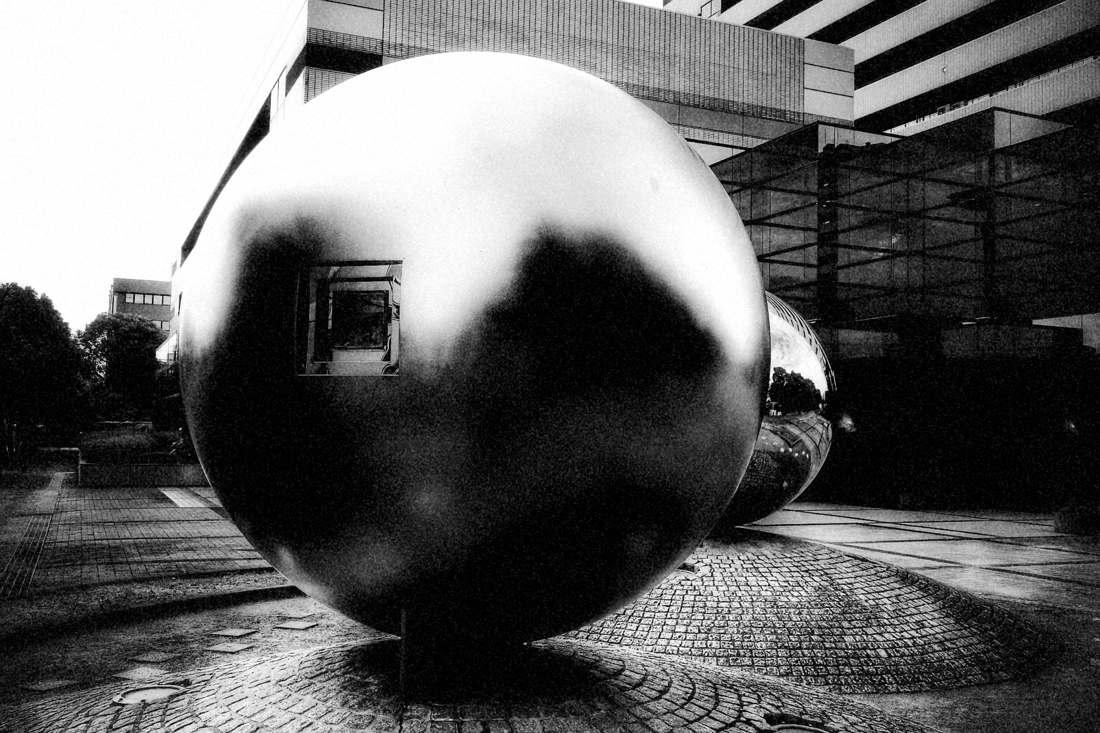 Grande sphère métallique en noir et blanc se tenant au milieu d'un paysage urbain