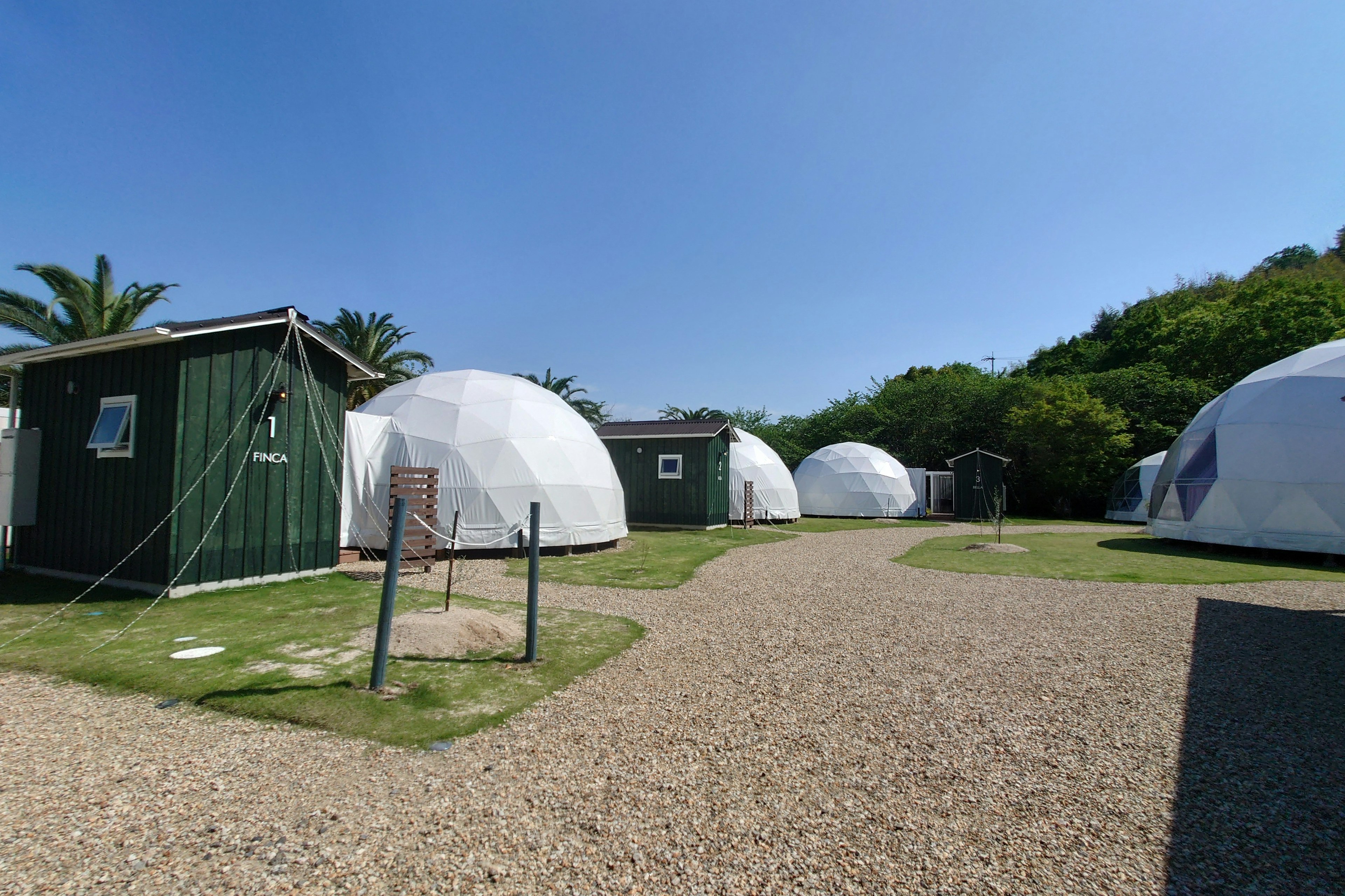 白色圓頂住宿的風景，周圍是綠色小屋和晴朗的藍天