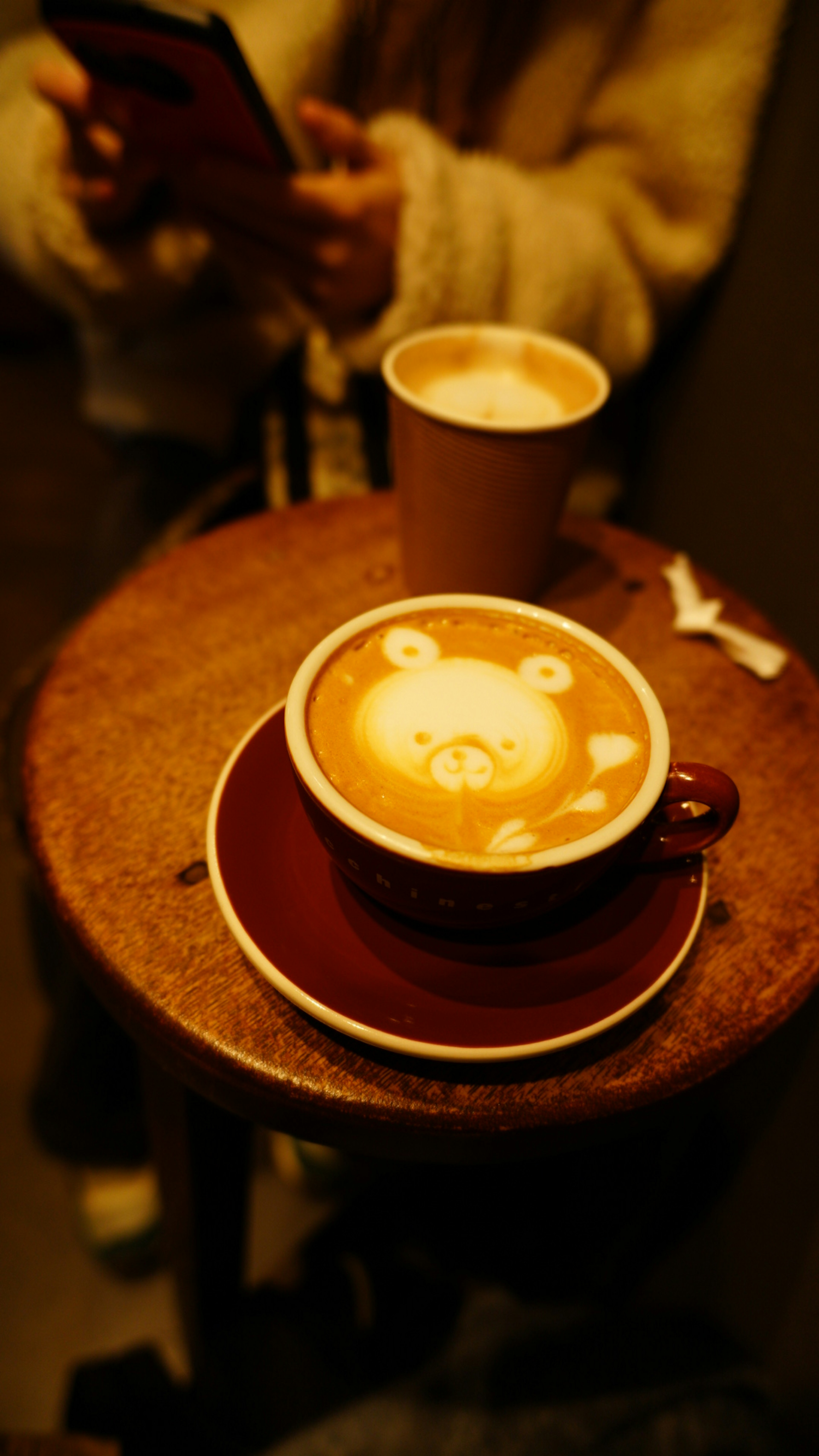 Kaffeetasse mit Latte Art auf einem Holztisch und Pappbecher