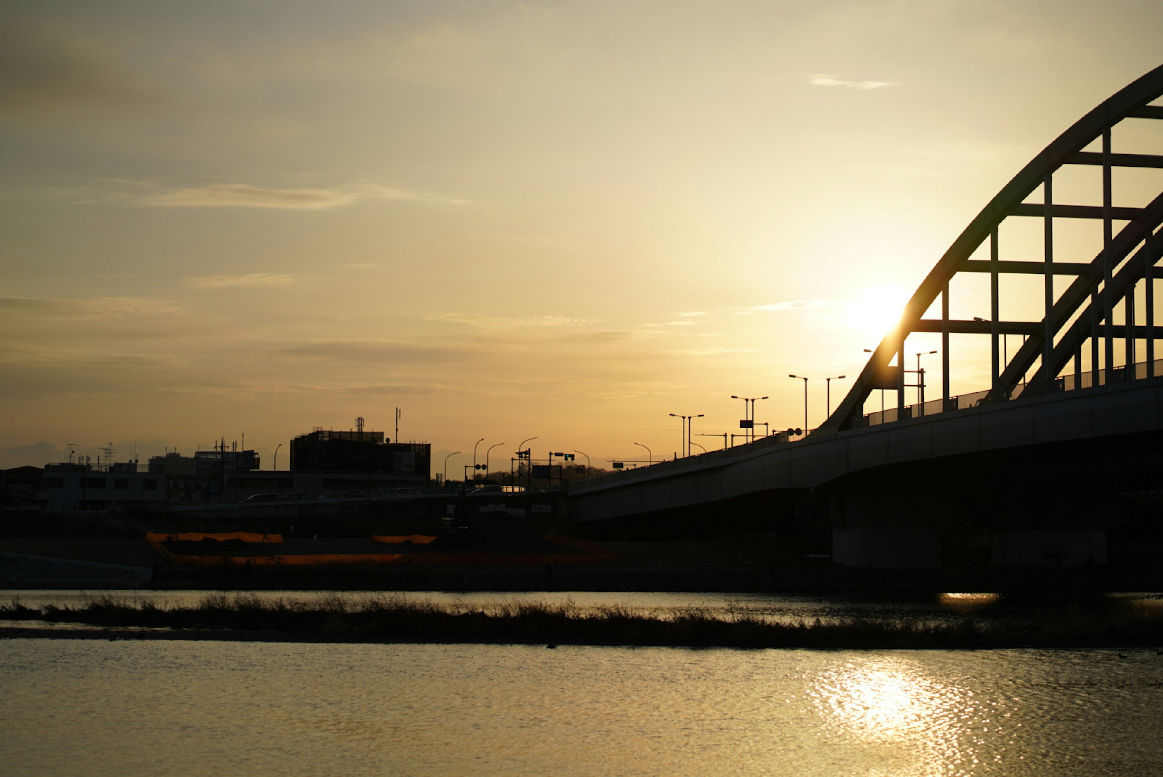 Siluet jembatan di atas sungai saat matahari terbenam